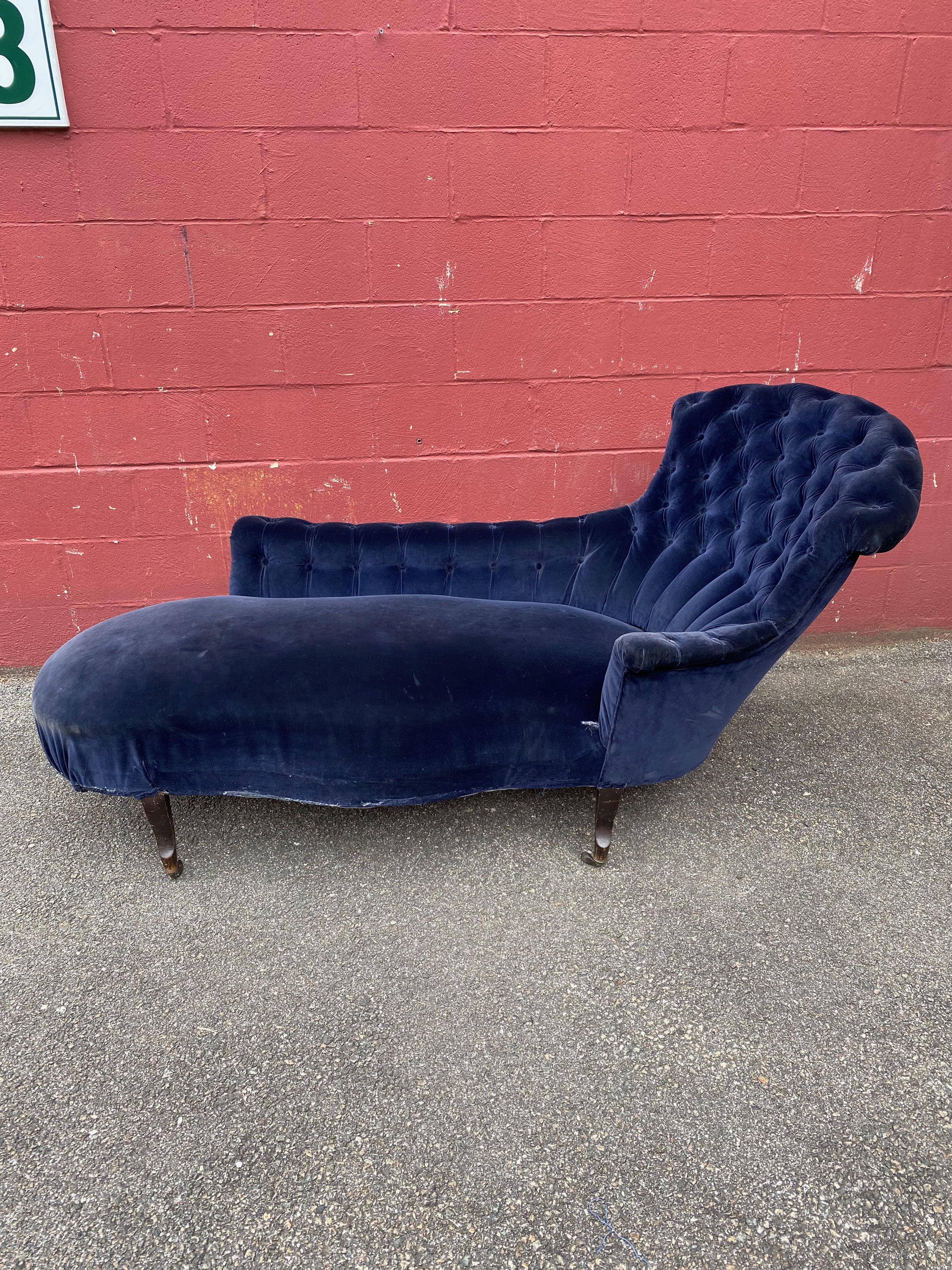 An unusual asymmetrical French Napoleon III chaise lounge in dark blue velvet. The chaise lounge originally had matching with bullion fringe but has been removed, please see photos. The back and arms of this piece are tufted.  This piece needs to be