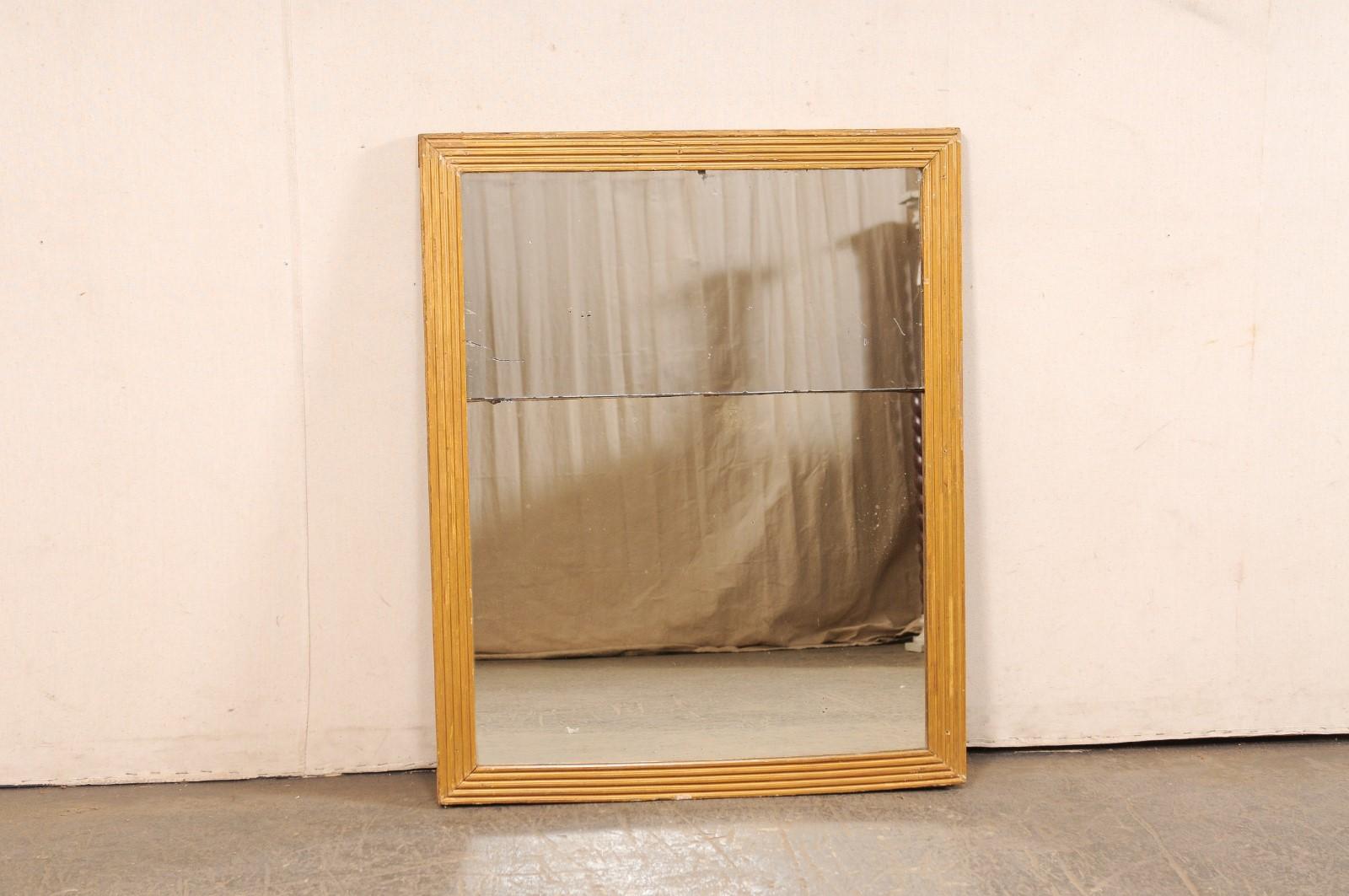 Miroir mural français en or, avec son verre et sa finition d'origine, du 19e siècle. Ce miroir ancien de France présente un design épuré/minimaliste avec un cadre en bois de forme rectangulaire composé d'une sculpture linéaire cannelée sur le