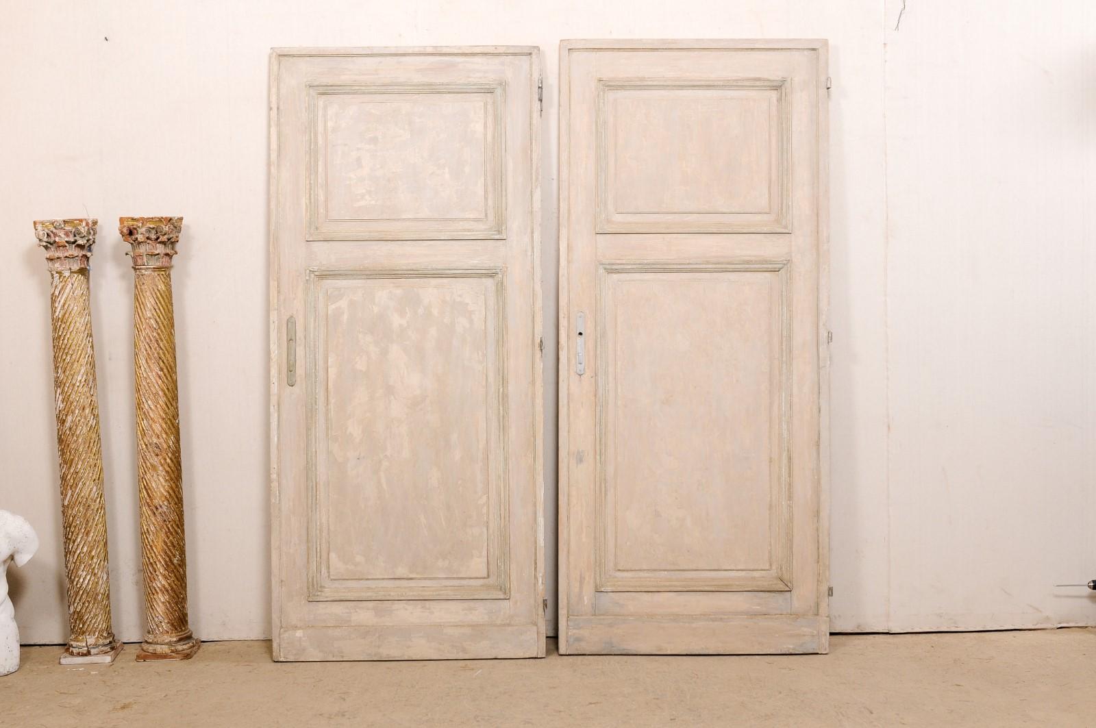 A French set of two doors, both singles, from the 19th century. These antique doors from France, though not meant to match up together (as in a pair of French-style doors) but are two near-identical single doors. Each door is comprised of two