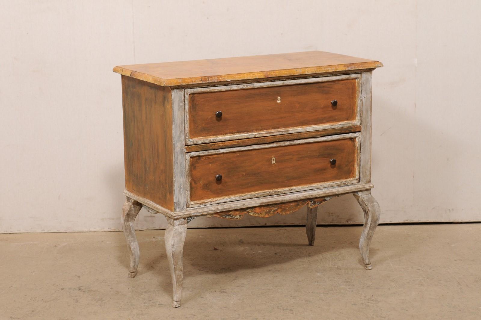 A French painted wood, raised two-drawer chest from the 19th century. This antique chest from France features a slightly overhanging faux-marble painted top, with case beneath consisting of two stacked, dovetailed drawers, a nice carved skirt along