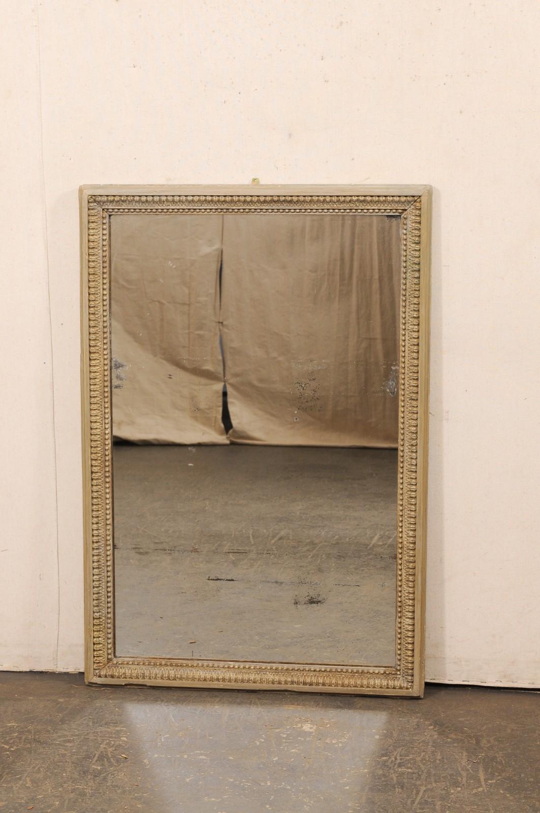 A French carved and painted wood wall mirror from the 19th century. This antique mirror from France features a molded wood frame, with straight/linear outer edge giving to a nicely carved inner surround with lamb's tongue trim and a sweet petite