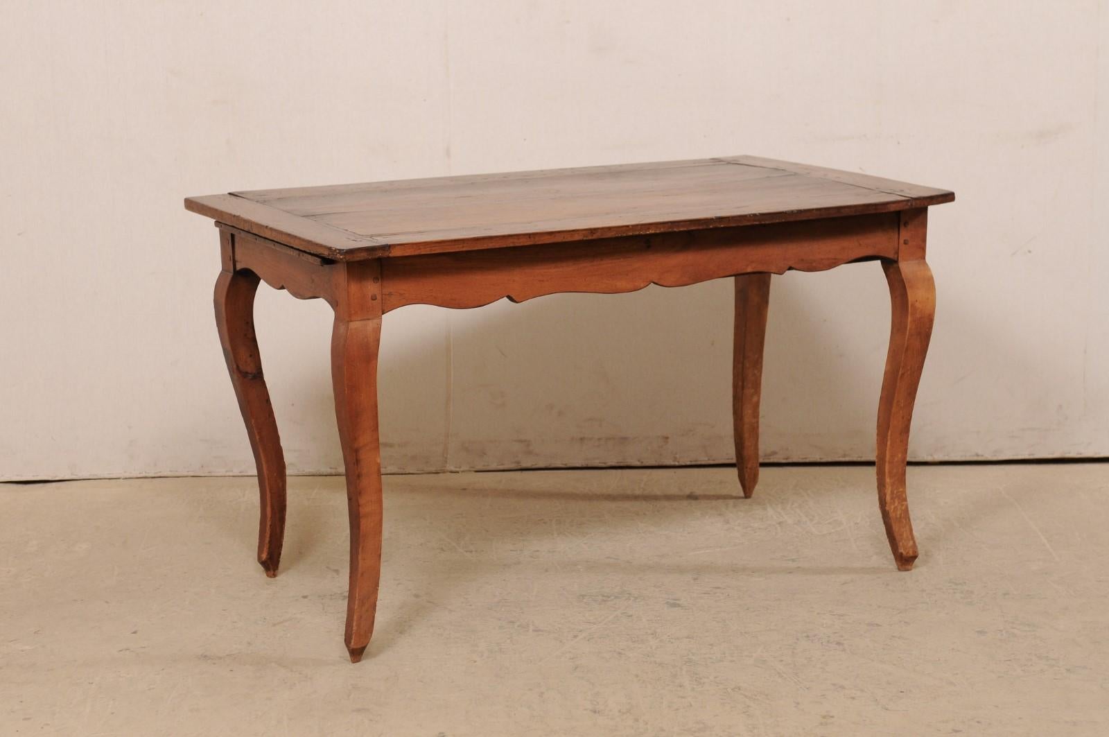 A French fruitwood table with single drawer and scalloped apron from the 19th century. This antique table from France features a rectangular-shaped top which overhangs a scallop-carved apron bellow which houses a single drawer at one short side and