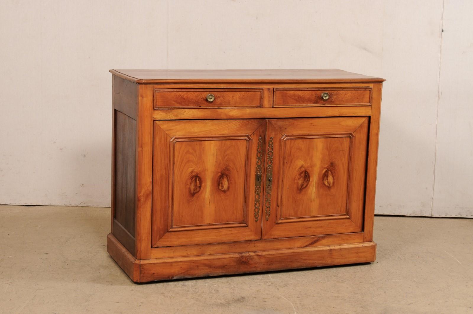 A French wooden buffet cabinet from the 19th century. This antique cabinet from France has a beautiful fruitwood grain shown throughout, which speaks to the simplistic and clean lines of the piece. The case houses a pair of half-sized drawers at