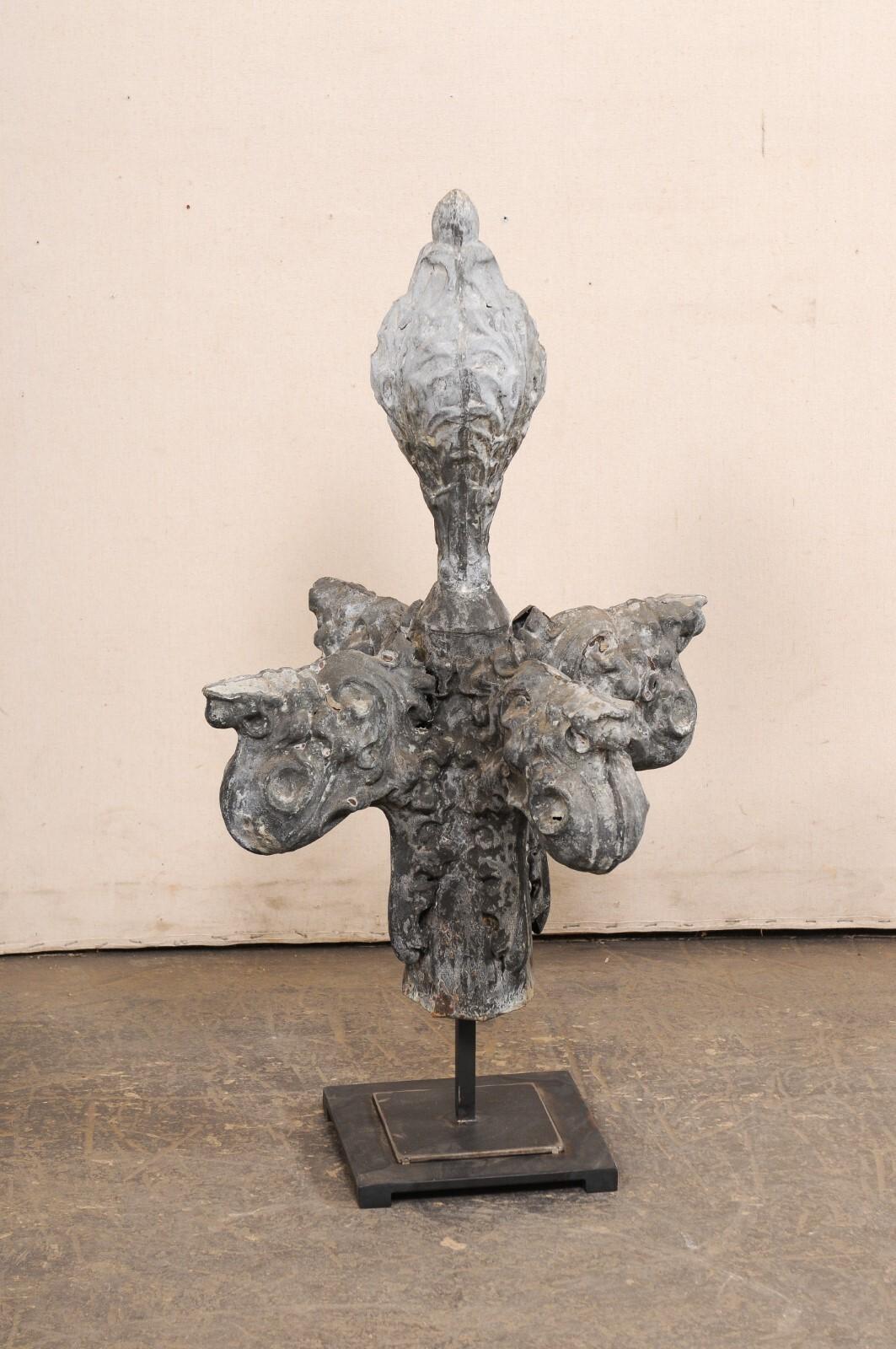 A French zinc finial fragment from the 19th century presented on custom stand. This antique decoration from France features a nicely detailed, three-dimensional, zinc architectural piece with four arms and top finial, adorn in acanthus leaf and