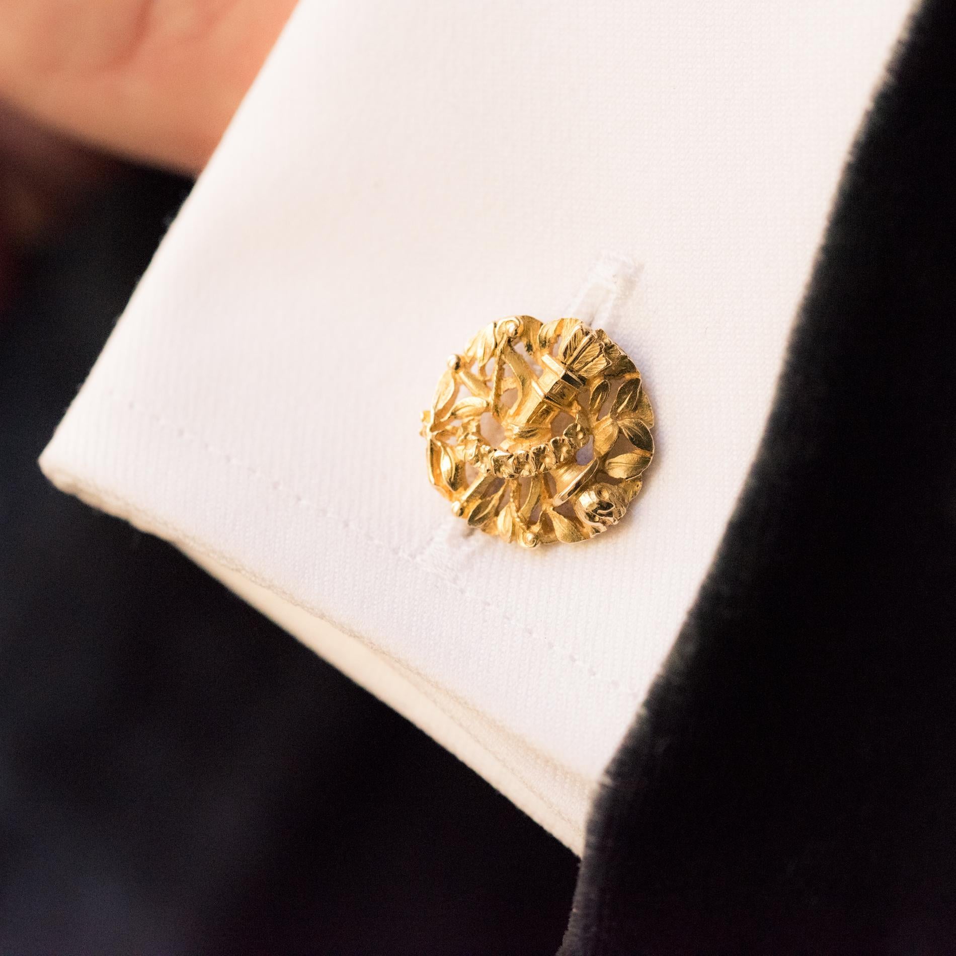 Pair of cufflinks in 18 karat yellow gold, eagle's head hallmark.
These cufflinks are round, perforated with a quiver and a hymenic torch on an openwork decoration of foliage and retained by a crown of roses. The central part is a curved rod with a