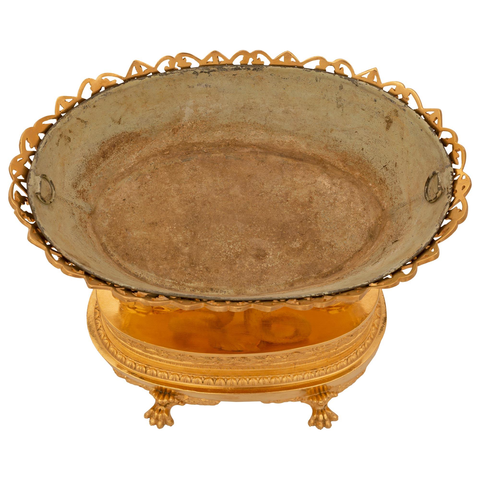 An exceptional and very high quality French 19th century 1st Empire period ormolu centerpiece. The oblong shaped centerpiece is raised by handsome paw feet amidst scrolled foliate designs below a most decorative mottled wrap around Coeur de Rai band