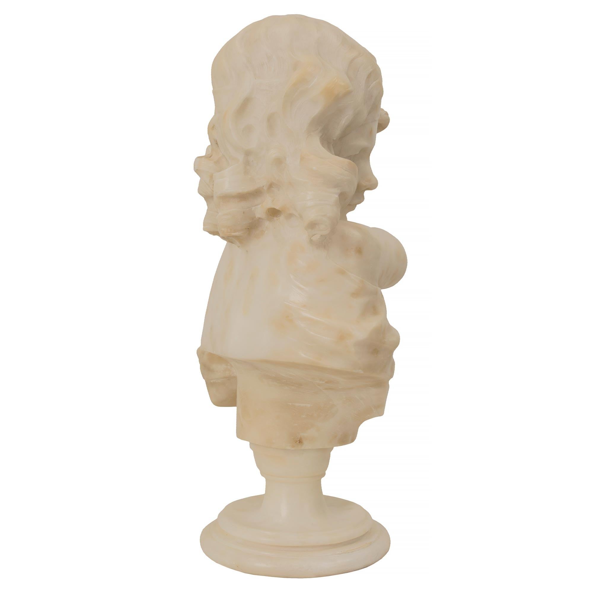 Magnifique buste de jeune femme en albâtre datant du 19e siècle. Le buste est surélevé par une base circulaire tachetée sous le piédestal en forme de socle. La belle jeune fille tient un carquois avec des flèches dans une main et a l'autre bras levé