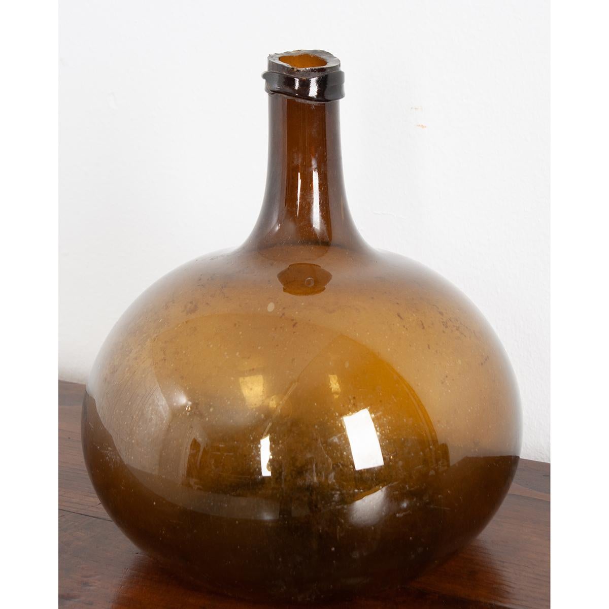 This amber color, blown glass wine keg, or demijohn as they are sometimes called, remains fully intact. Still in wonderful condition, this piece could be a vase and make a great addition to your space, giving it an element of texture and color.