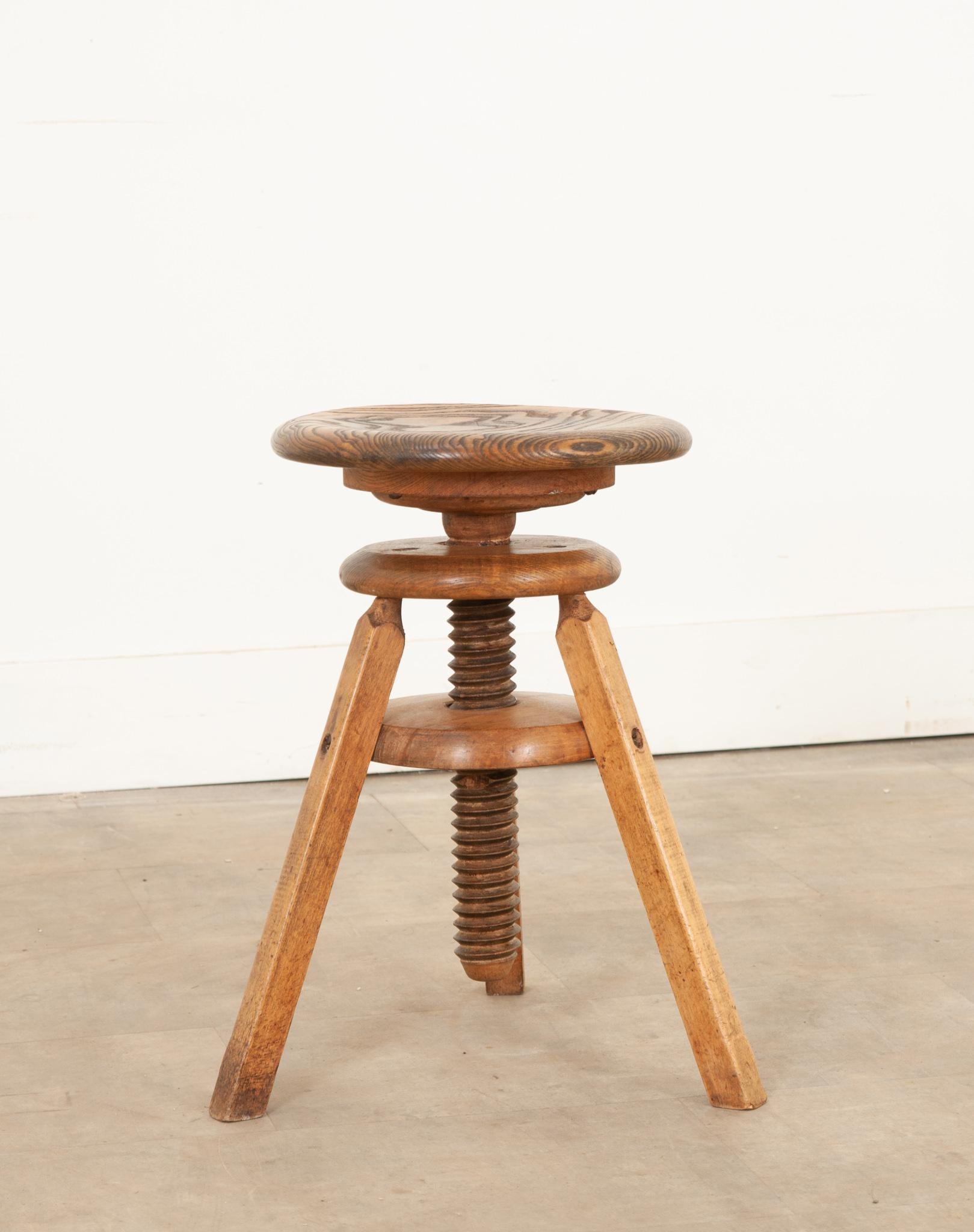 A French 19th century ash adjustable stool with a deep relief twisted-form central column that acts as the mechanism to adjust the height and three sturdy splayed legs. The large wooded screw attached to the seat allows the stool to change heights