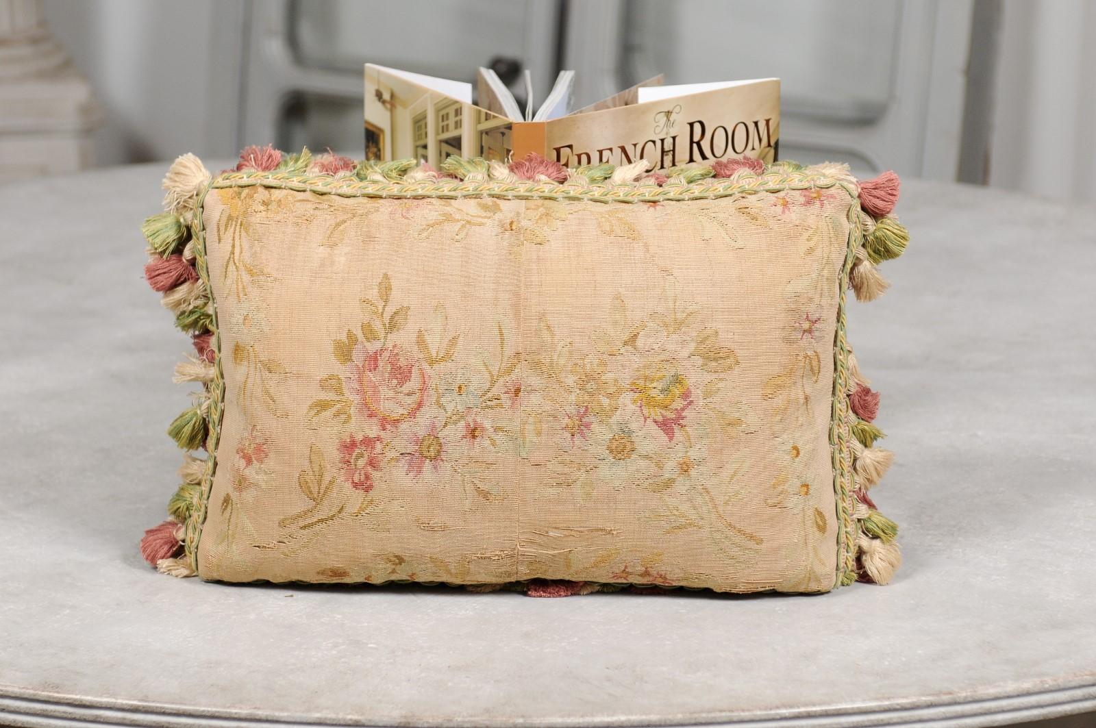 A French Aubusson tapestry pillow from the 19th century, with floral decor and tassels. Created during the 19th century in the Aubusson tapestry manufacture located in central France, this horizontal pillow features a delicate bouquet of pink roses
