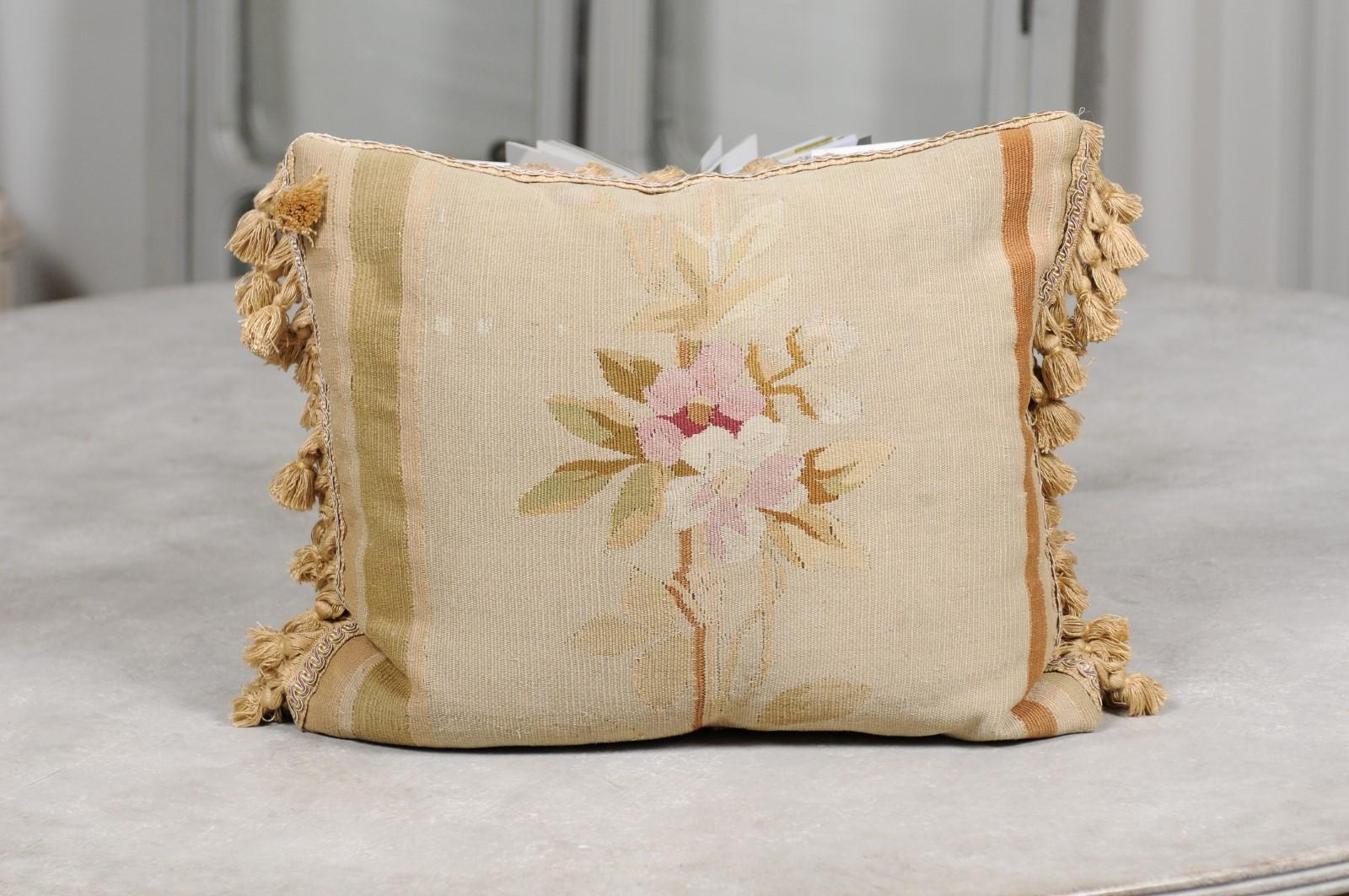 A French Aubusson tapestry pillow from the 19th century, with floral décor and tassels. Born during the 19th century in the Aubusson tapestry manufacture located in central France, this lovey pillow features a delicate décor showcasing a bouquet of