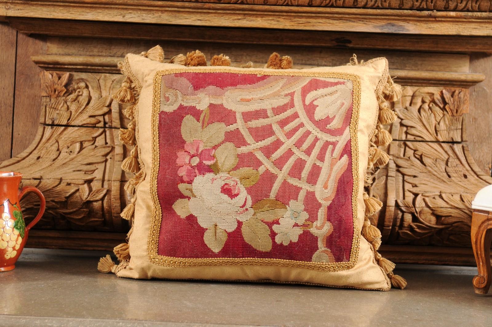 A French Aubusson tapestry pillow from the 19th century, with floral motifs, gallon trim and petite tassels. Created during the 19th century in the Aubusson tapestry manufacture located in central France, this pillow features delicate flowers on a