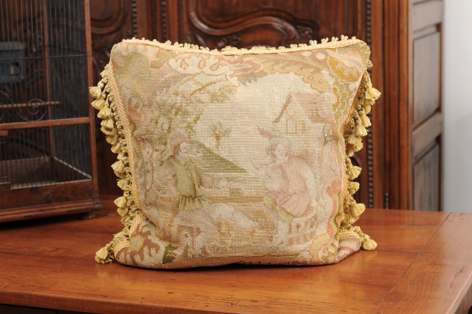 A French Aubusson tapestry pillow from the 19th century, with medieval style genre scene and tassels. Woven during the 19th century in the Aubusson tapestry manufacture located in central France, this exquisite pillow features a joyous scene