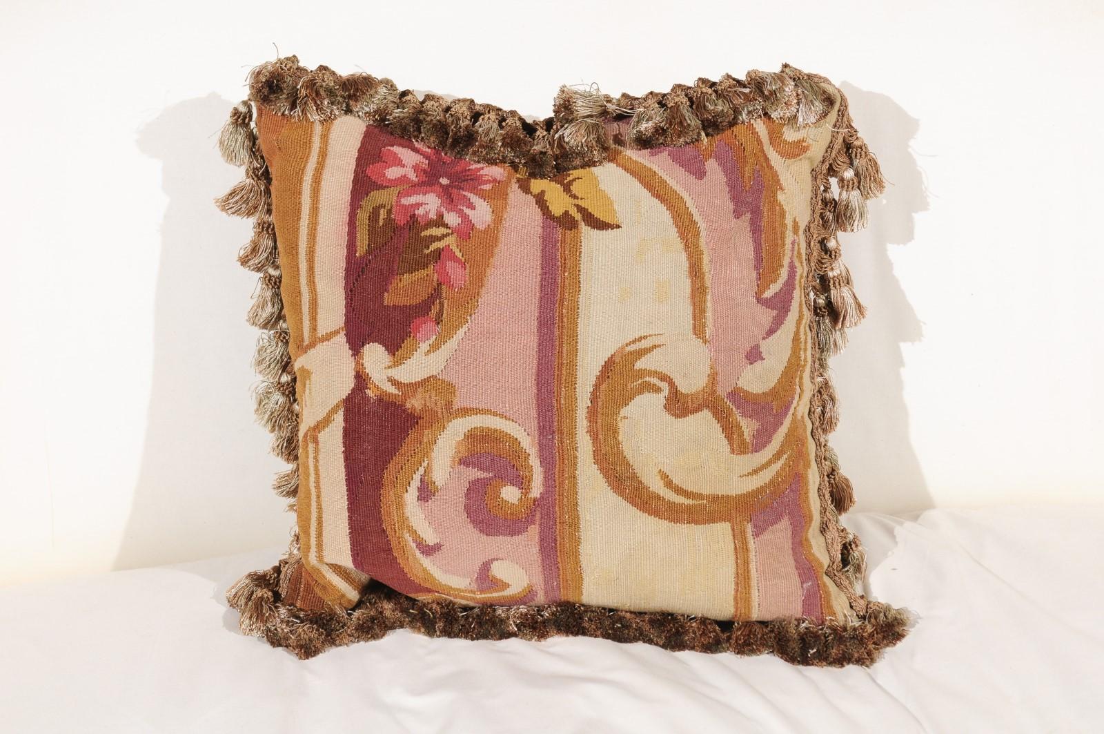 A French Aubusson tapestry pillow from the 19th century, with floral décor and scrolling foliage. Born during the 19th century in the Aubusson tapestry manufacture located in central France, this pillow features eye-catching volutes separated from