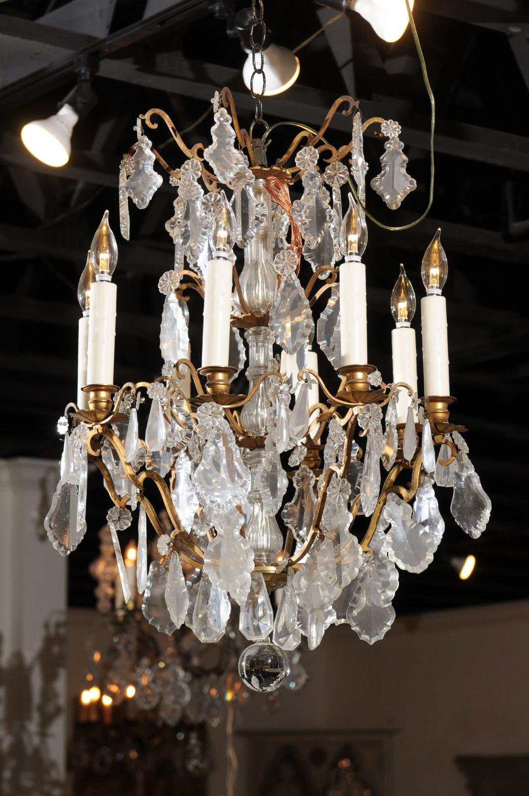 A French eight-light Baccarat crystal chandelier from the 19th century, with scrolling brass armature. Born in the Lorraine region of France in the Baccarat manufacture, this exquisite chandelier features a central crystal column connected to a