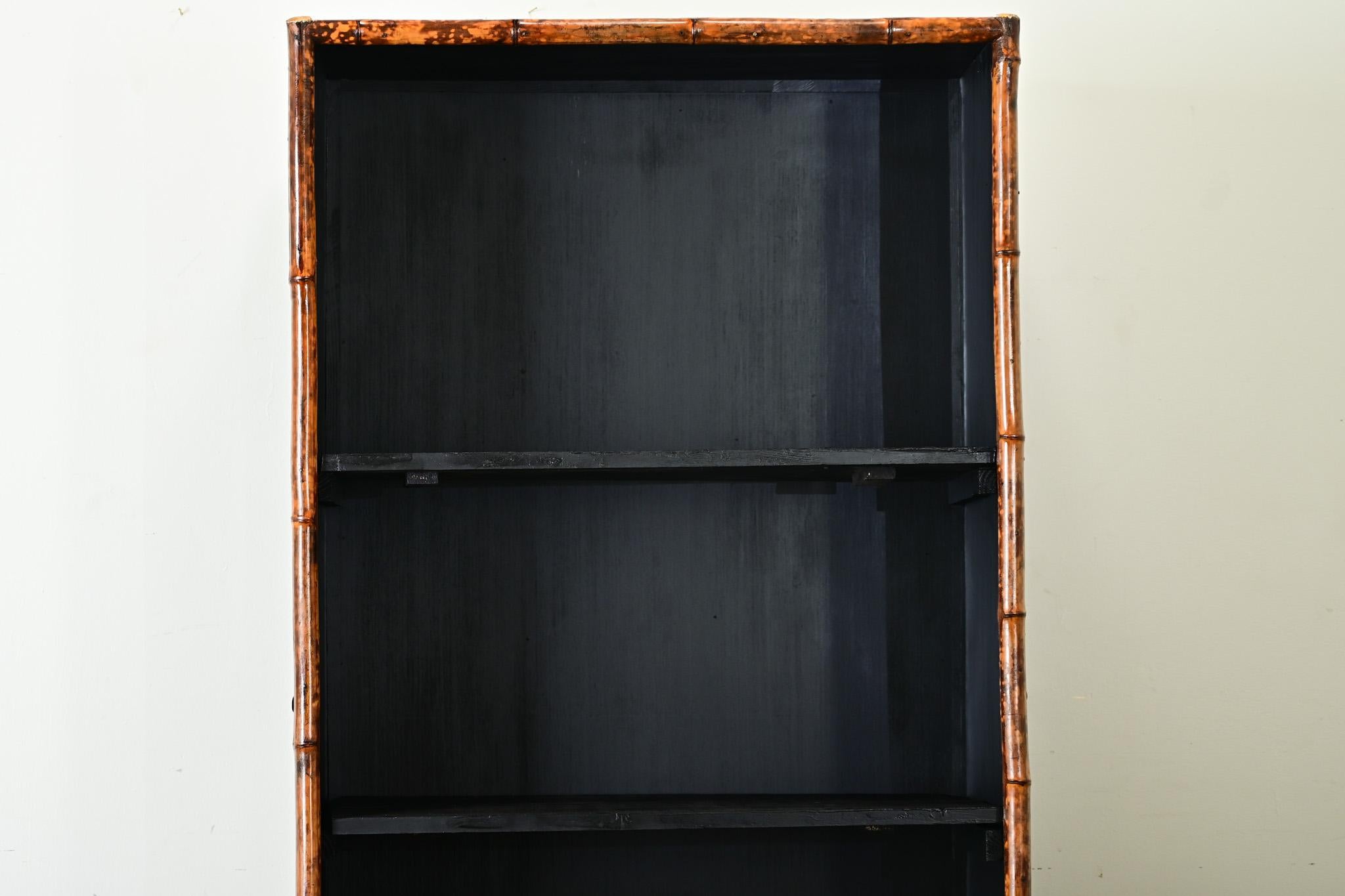This English bamboo bookcase from the Aesthetic Movement of the late 1800s was given a creative update with recent decoupage and painted ebony finish. Schools of fish animate the exterior surfaces, their glowing honey color is a perfect match to the