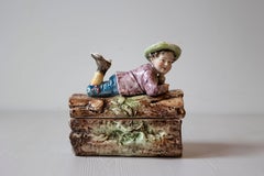 French 19th Century Barbotine Bonbon Box Depicting a Boy Laying on a Tree Trunk