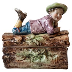 French 19th Century Barbotine Bonbon Box Depicting a Boy Laying on a Tree Trunk