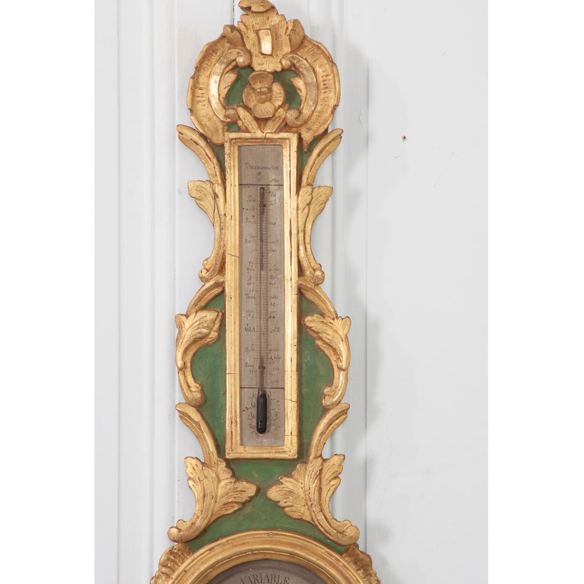 French 19th painted and gold gilt barometer and thermometer. It is a recognizable ‘banjo’ shaped scientific instrument with all the carved details in gold gilt and the background is painted a sage green. The circular face has painted numbers and