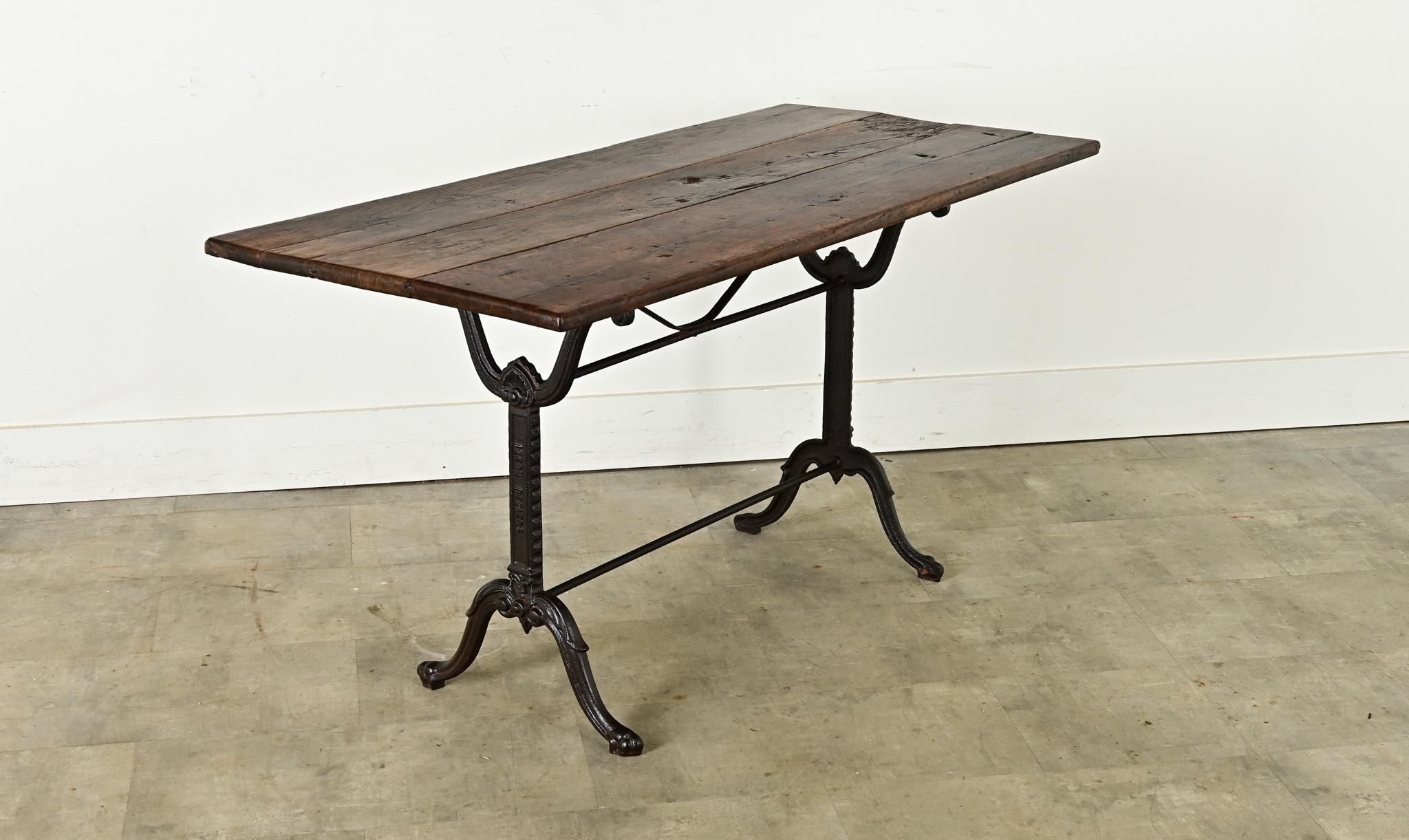 Une table de bistrot française exceptionnelle avec des détails d'époque Beaux Arts dans la base en fonte. Le plateau en chêne foncé présente une surface bien patinée, conforme à l'âge et au type d'utilisation. Des motifs néoclassiques apparaissent