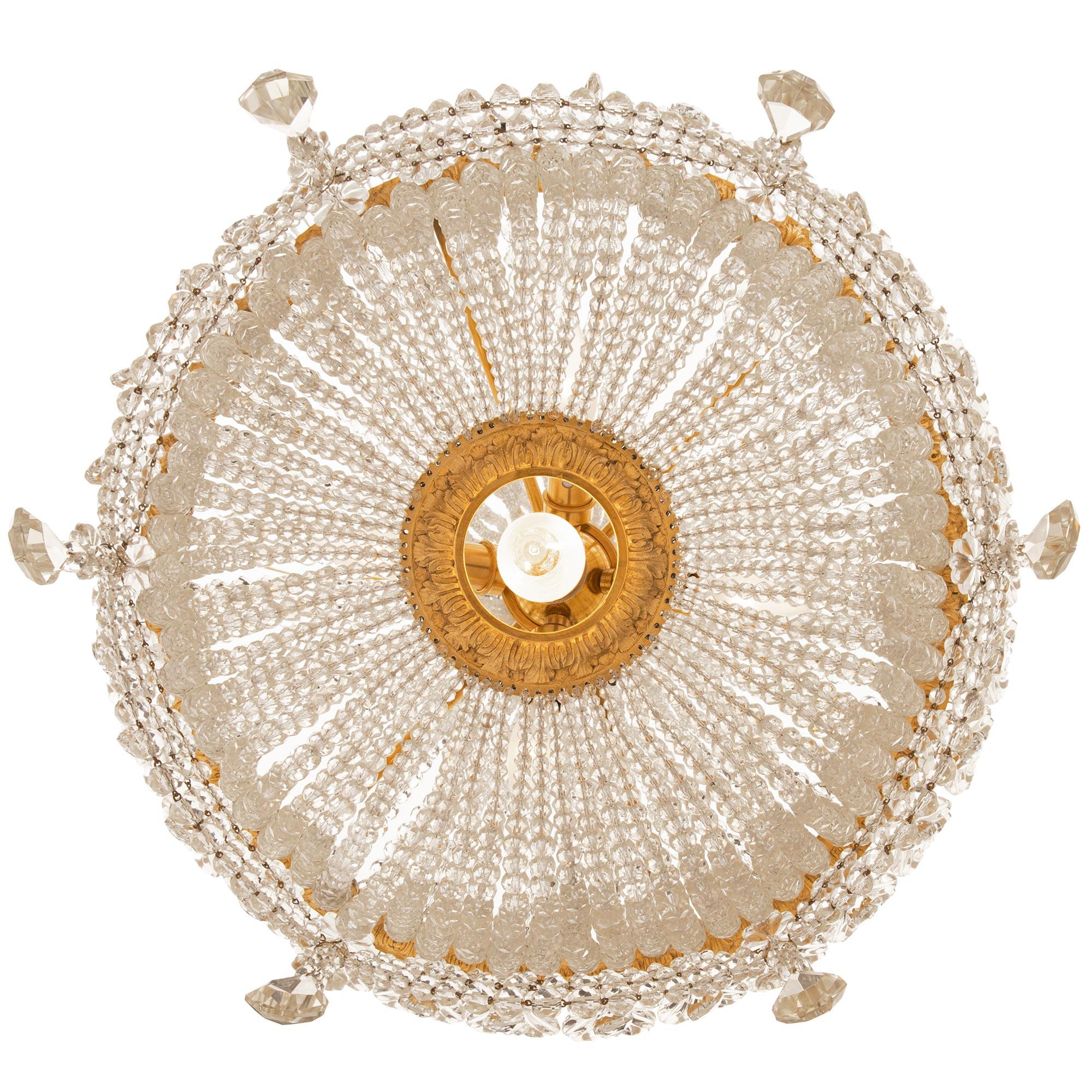 A stunning and extremely decorative French 19th century Louis XVI st. Belle Époque period Baccarat crystal and ormolu chandelier. The seven light chandelier is centered by a unique hanging central light bulb surrounded by a lovely richly chased wrap