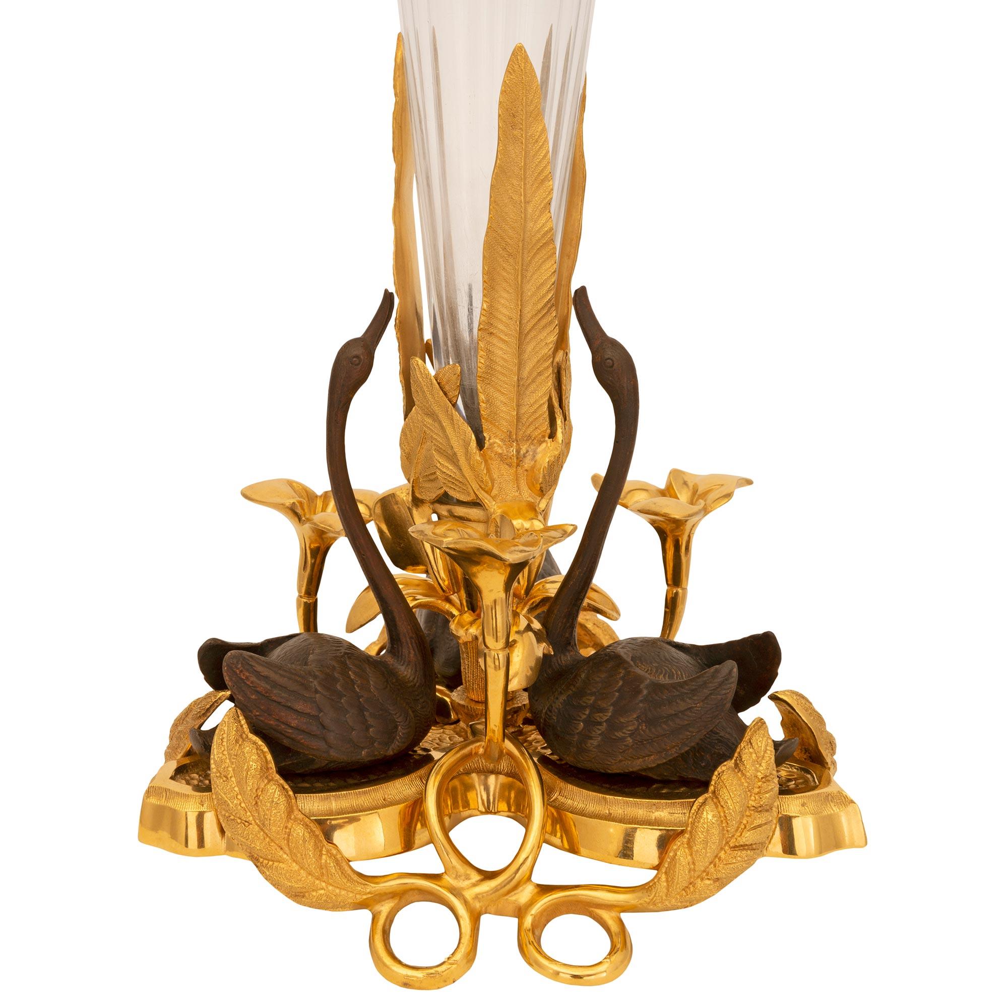 Un charmant et très élégant vase en bronze doré, bronze patiné et cristal de Baccarat, d'époque Louis XVI et Belle Époque. Le magnifique vase est surélevé par une base percée en bronze doré avec de fins mouvements feuillagés, de jolis nénuphars, des