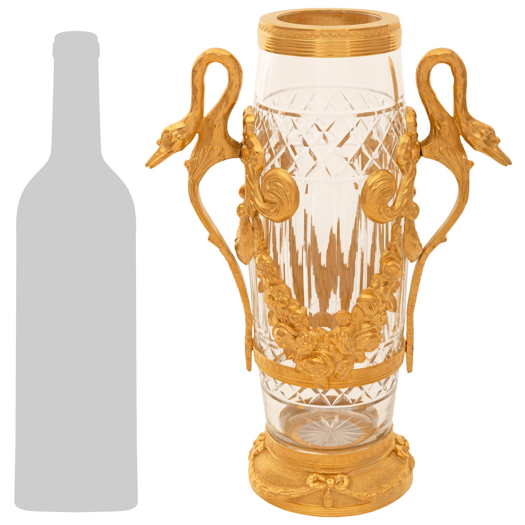 Un elegante e pregiato vaso in cristallo e ormolo del XIX secolo di French Belle Epoque. Lo splendido vaso è sollevato da una base circolare in Ormolu con ghirlande di alloro legate da fiocchi al di sopra di una fascia di lamelle e al di sotto di
