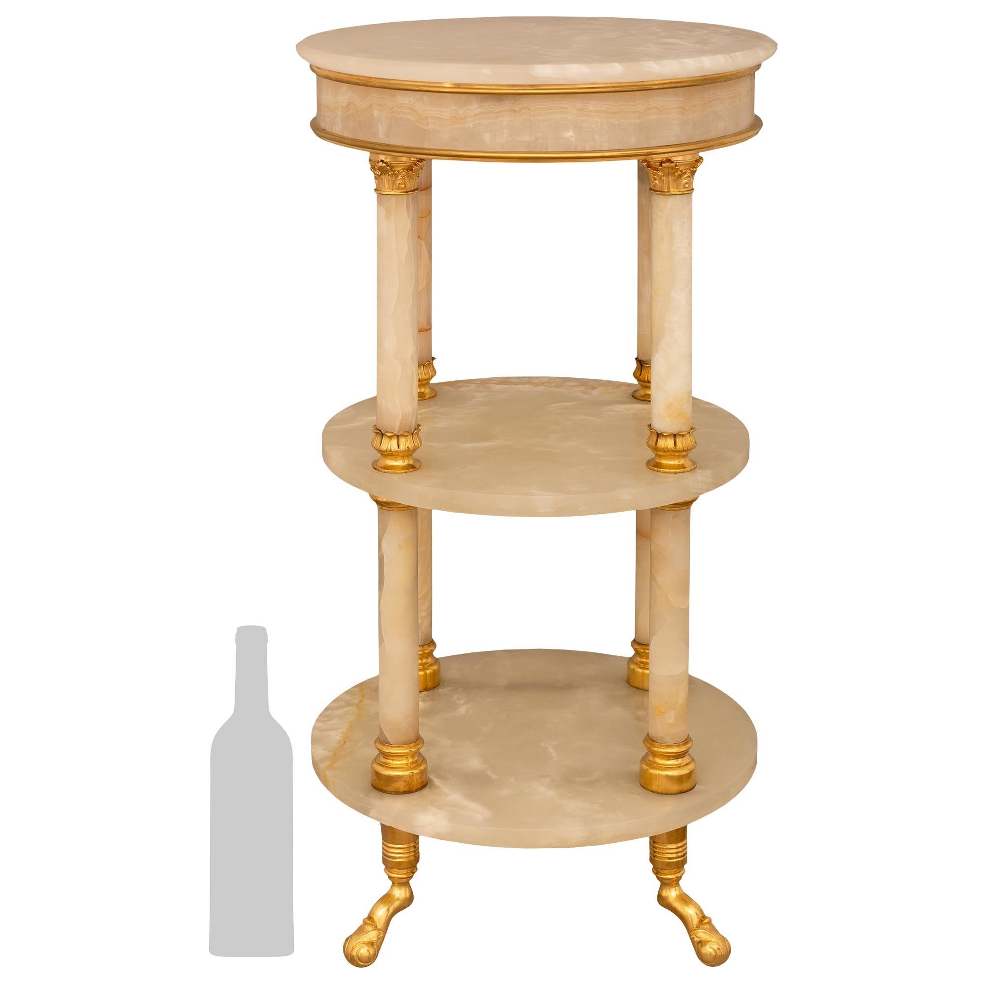 Superbe et très décorative table d'appoint en onyx et bronze doré d'époque Louis XVI, XIXe siècle, Belle Époque. Cette magnifique table d'appoint circulaire à trois niveaux repose sur quatre pieds angulaires décorés de feuilles d'acanthe enroulées.