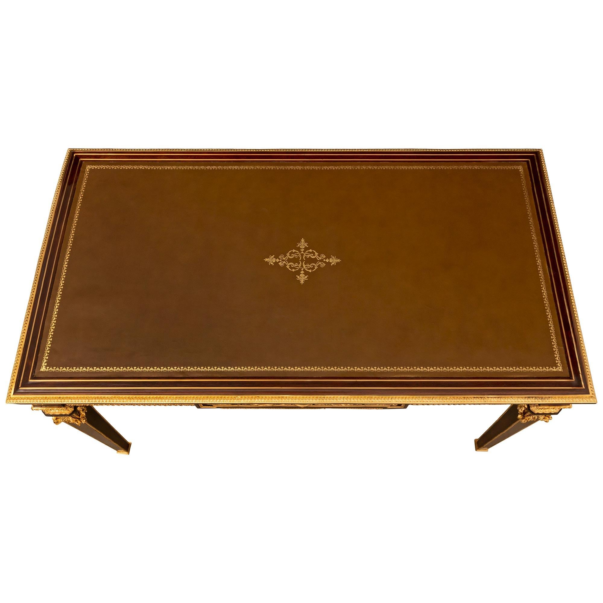 A striking and very high quality French 19th century Louis XVI st. Belle Époque period Mahogany, brass and ormolu desk after a model by Jean-Henri Riesener and attributed to François Linke. The one drawer desk is raised by elegant square tapered