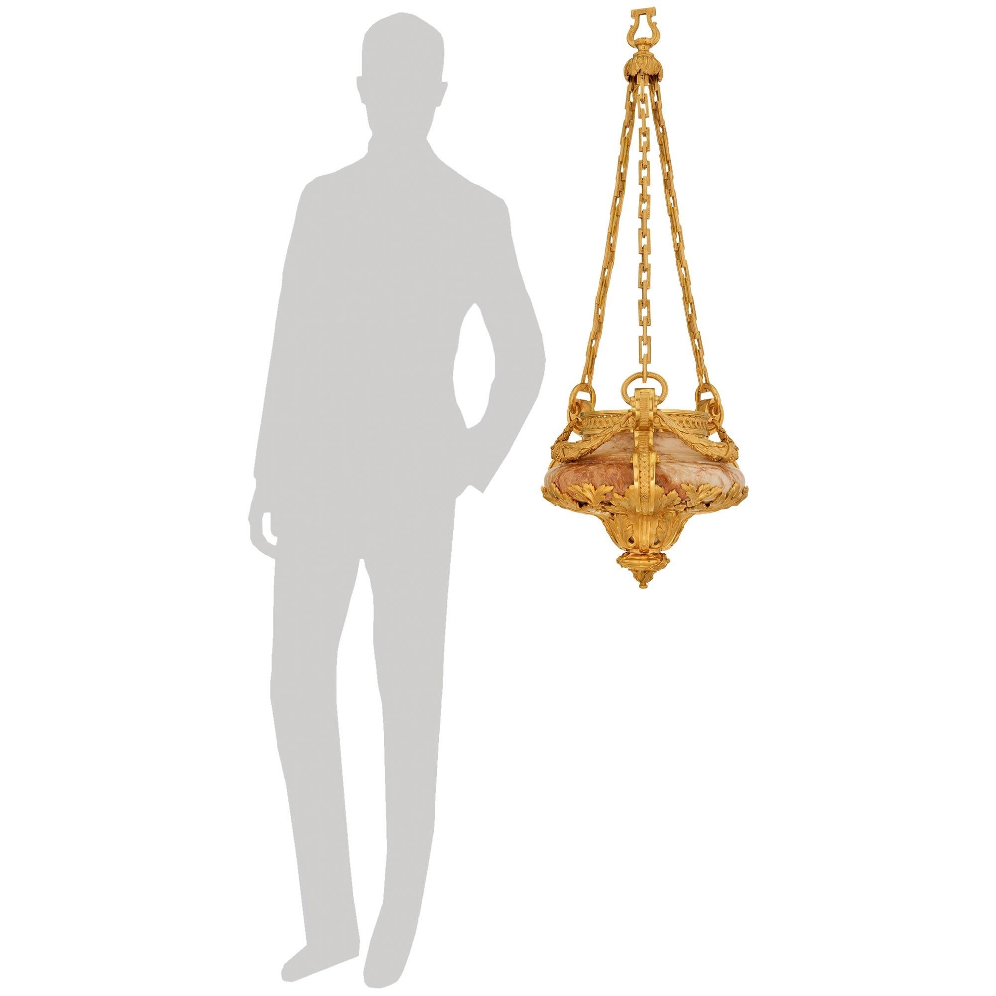 Uno straordinario e unico lampadario francese del XIX secolo in marmo Nuvolato Rosso e Ormolu del periodo Belle Epoque. Questo lampadario a sei luci, bello e di grande effetto, è centrato in basso da un terminale foliato a forma di toupie, con una
