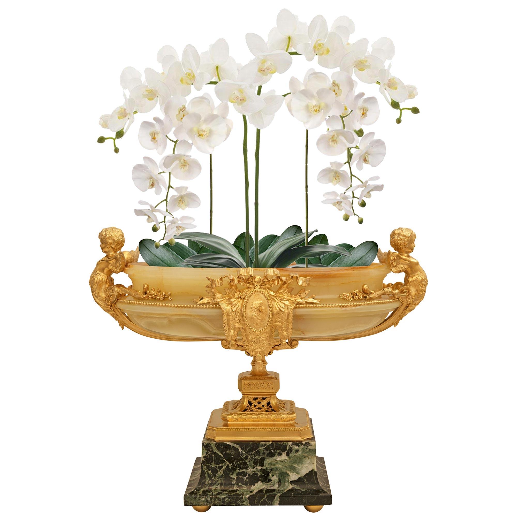 Un delizioso e pregiato centrotavola in onice, marmo Verde Antico e ormolu di epoca French Belle Epoque del XIX secolo. Questo splendido centrotavola è sollevato da quattro semisfere in Ormolu che elevano una base quadrata in marmo Verde Antico con