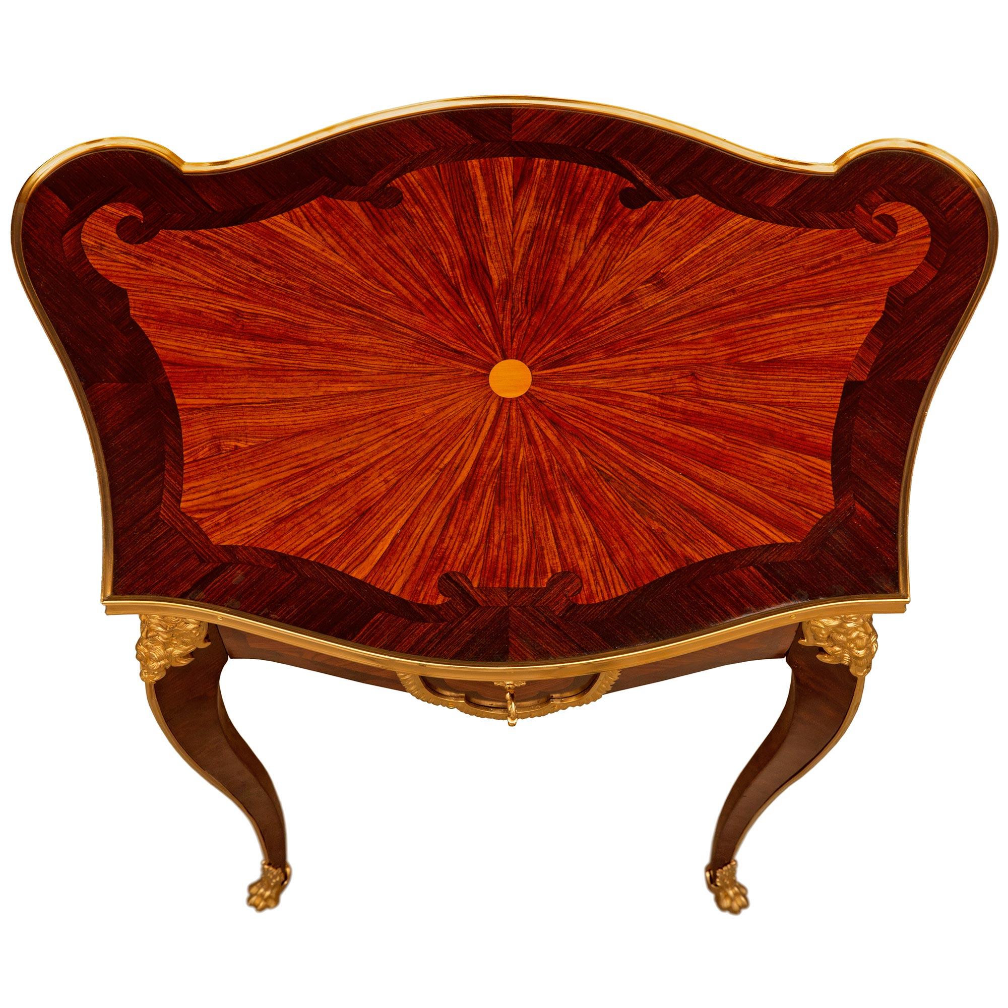 A uniquely shaped and high quality French 19th century Belle Epoque period Louis XV st. Tulipwood, Kingwood and ormolu side table. The table is raised by four slender cabriole legs decorated with a top ormolu mount of a bearded masculine mask above