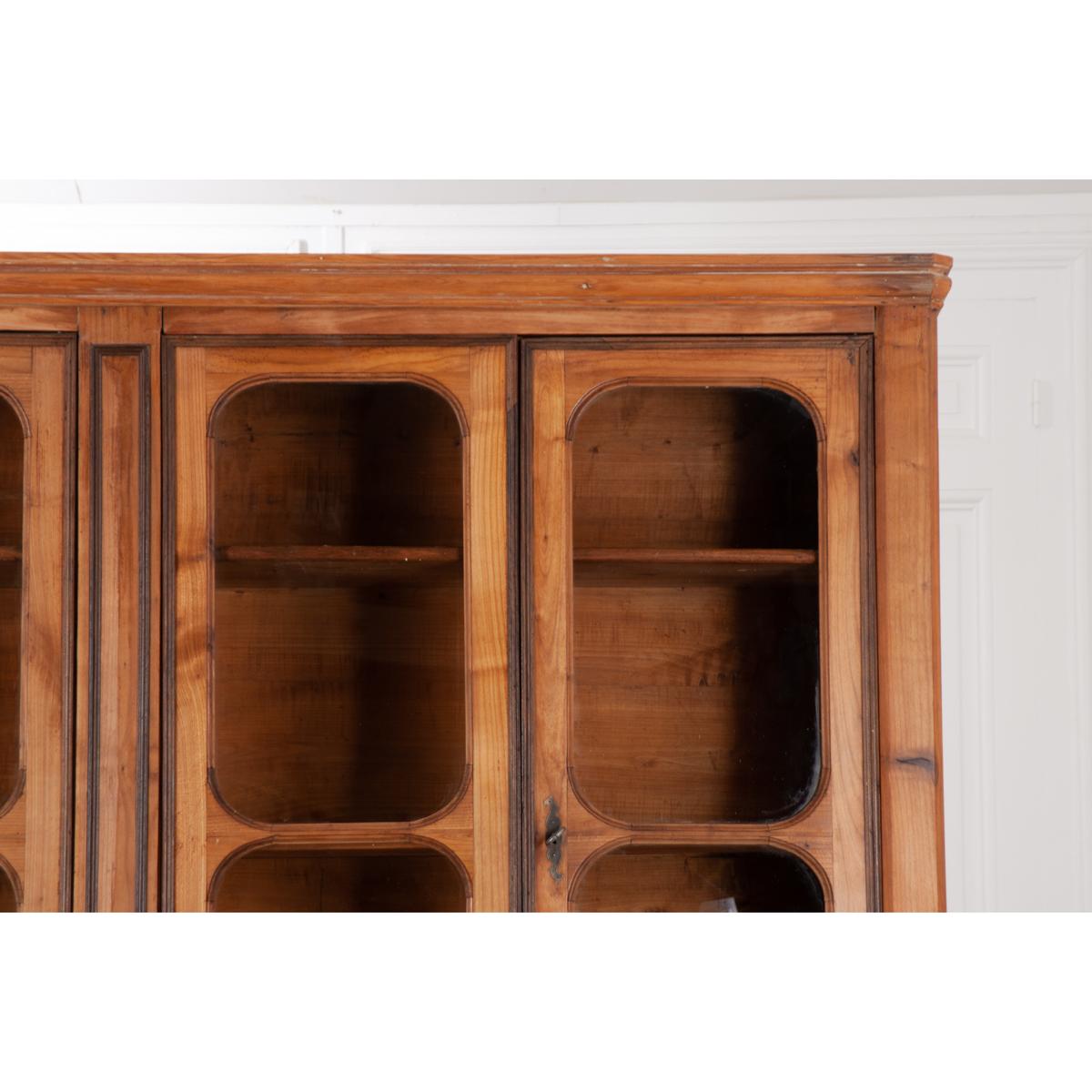 This Louis Philippe inspired bibliotheque is made of solid pine with walnut trim. It has eight doors and four drawers. The four glass front, locking and latching upper doors close before three adjustable full length shelves. There are two keys that