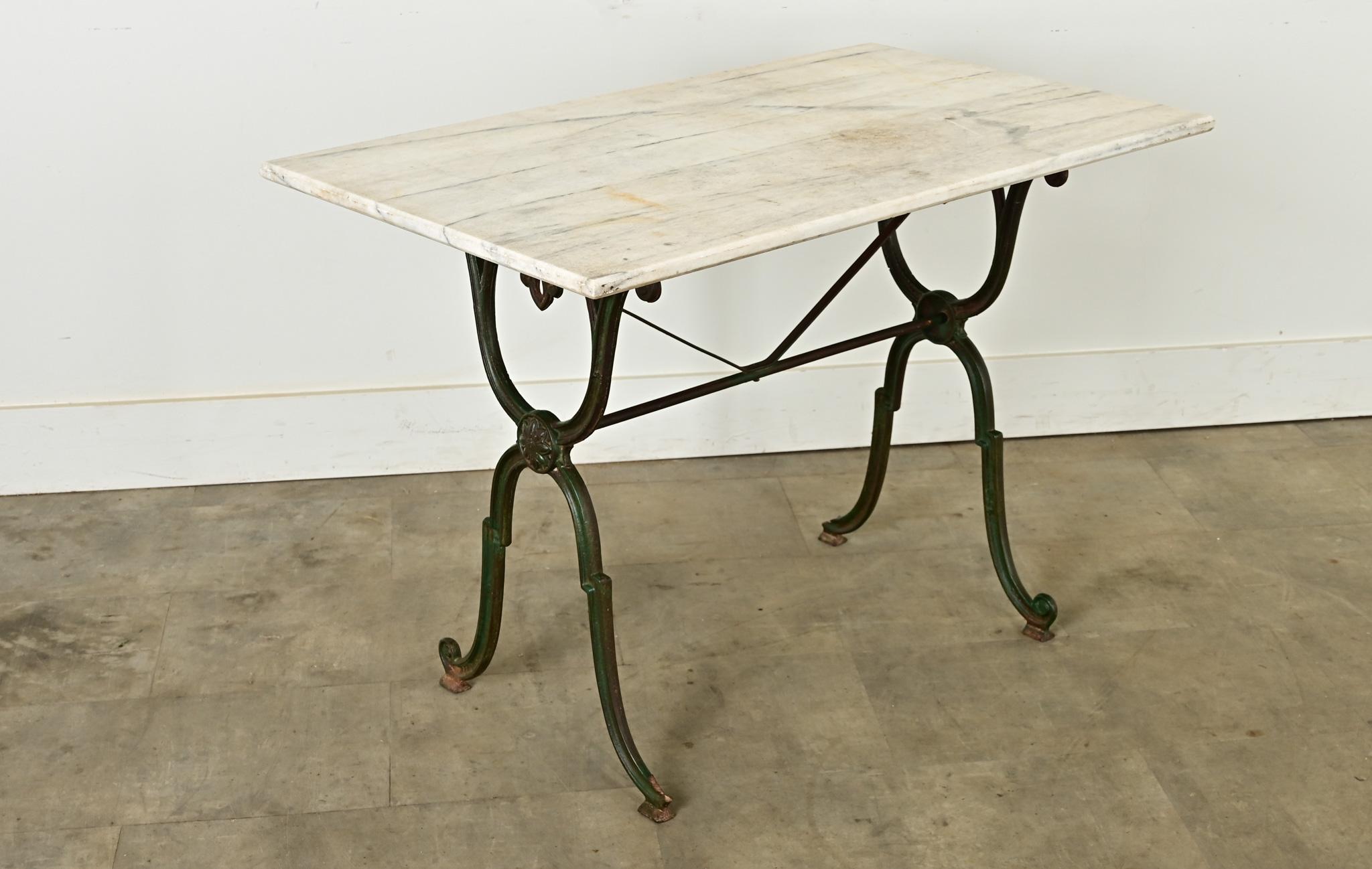 An original French brasserie table, circa 1890, with a removable white marble top on a cast iron frame. This classic French bistro table has a few design elements to stand out from the rest! The stone top features beveled edges around both the top