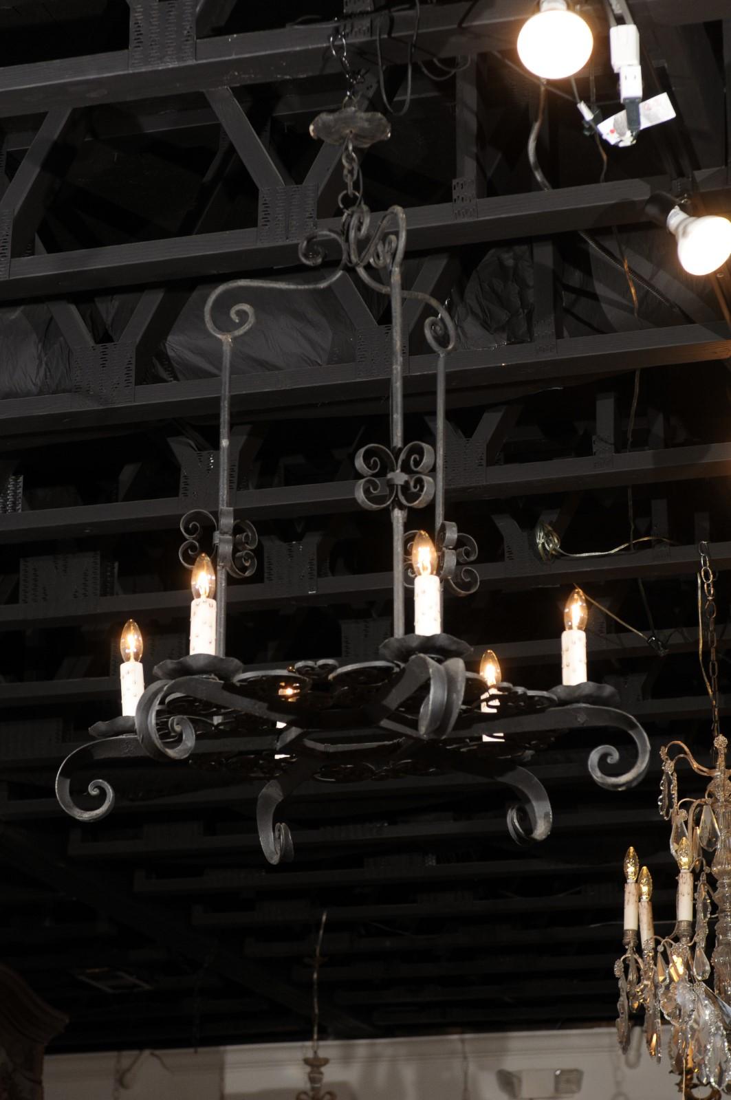 A French black iron six-light chandelier from the 19th century, with scrolled motifs. Crafted in France during the politically dynamic 19th century, this six-light chandelier showcases a black iron structure boasting a lovely patina, perfectly