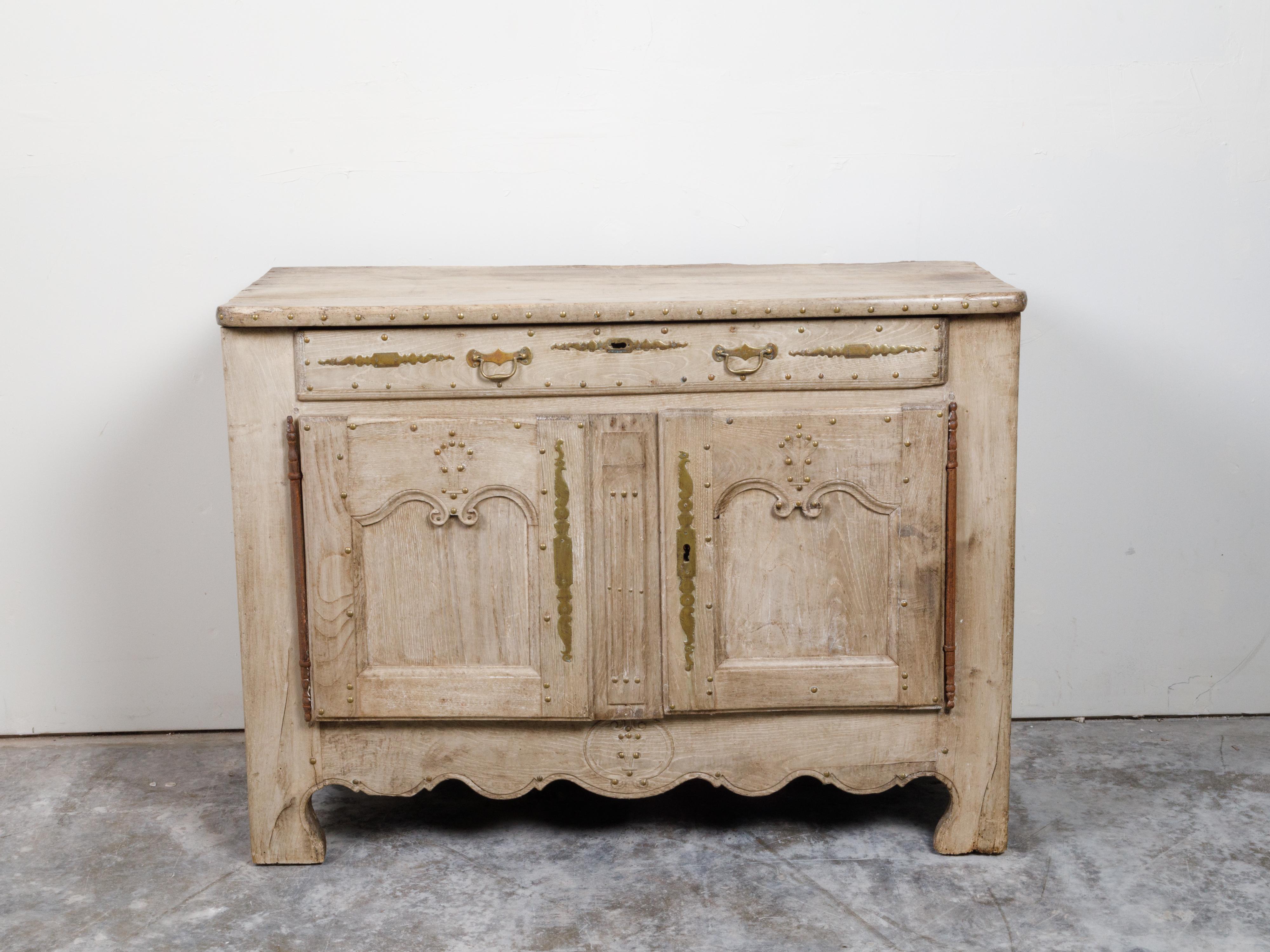 A French bleached wood buffet from the 19th century, with carved apron and nicely distressed patina. Created in France during the 19th century, this bleached wood buffet features a rectangular top with rounded corners and brass studs, sitting above