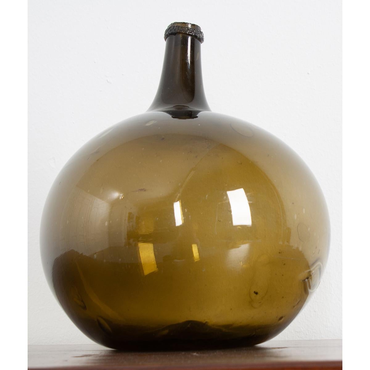 This green, blown glass wine keg, or demijohn as they are sometimes called, remains fully intact. Still in wonderful condition, this piece could be a vase and make a great addition to your space, giving it an element of texture and color.
  
