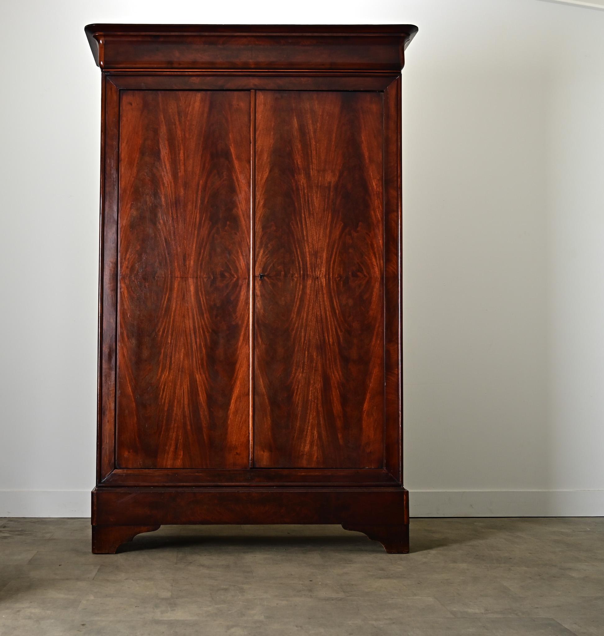 Ein geräumiger französischer Schrank im Louis-Philippe-Stil aus dem 19. Jahrhundert, handgefertigt aus Mahagoni mit vier buchförmig angeordneten Türen, die aus jeder Perspektive faszinieren, sowohl geometrisch als auch organisch. Dank der klaren,