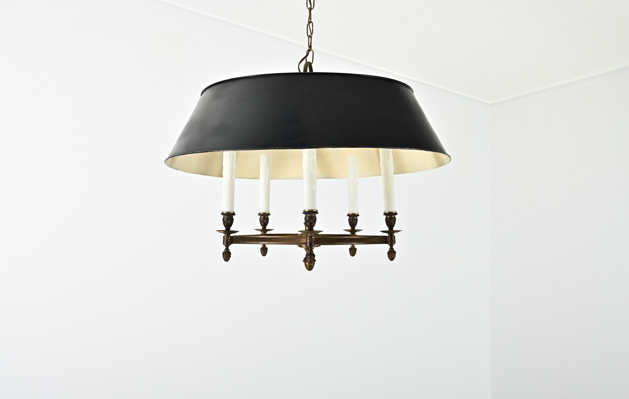 Un lampadario francese del XIX secolo in ottone e tole, nel classico stile bouillotte, per illuminare dolcemente un foyer o una zona pranzo. Cinque bracci di candele disposti a pentagramma concavo sono parzialmente nascosti dal paralume a tamburo in