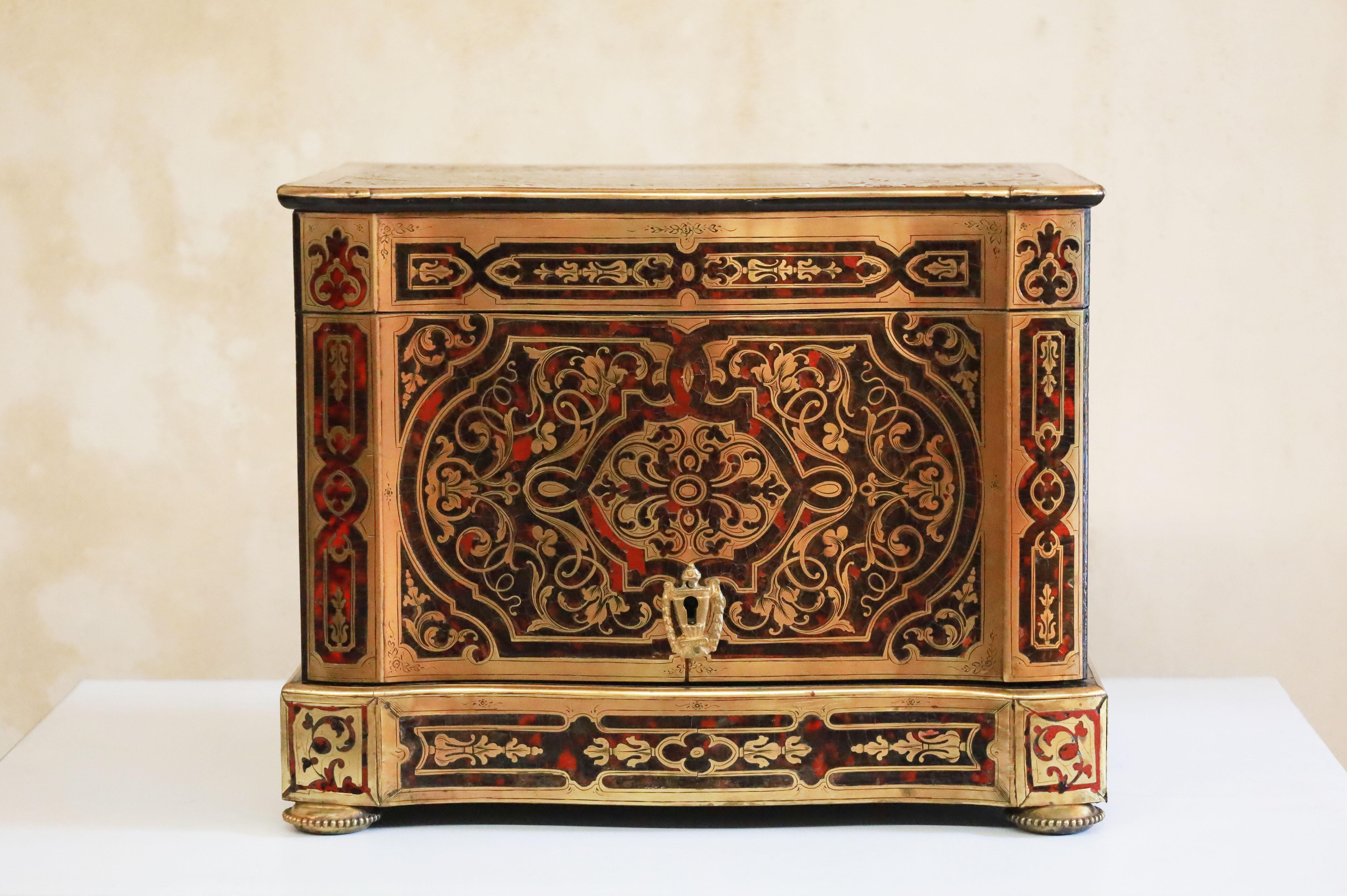 French 19th century Louis Philippe Boulle cave a liqueur. Made of  Tortoiseshell, brass, and ebonized Fruitwood. Inlaid floral elements on a Tortoiseshell  and wood.

 The top lifts up and locks in place while the front folds in to showcase the