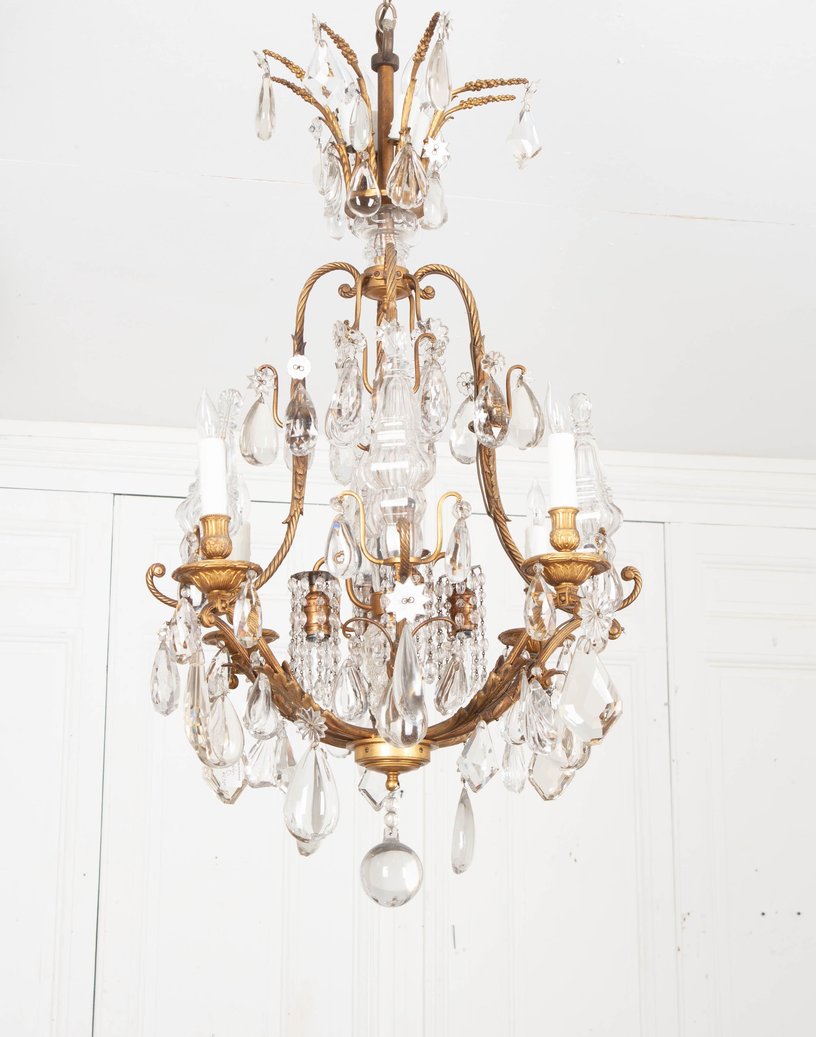 An outstanding French 19th century brass and crystal twelve light birdcage-form antique chandelier. Eight twisted rope scrolled arms extend to brass bobeche drip pans with four candle light sconces and four decorative glass baluster finials. Their