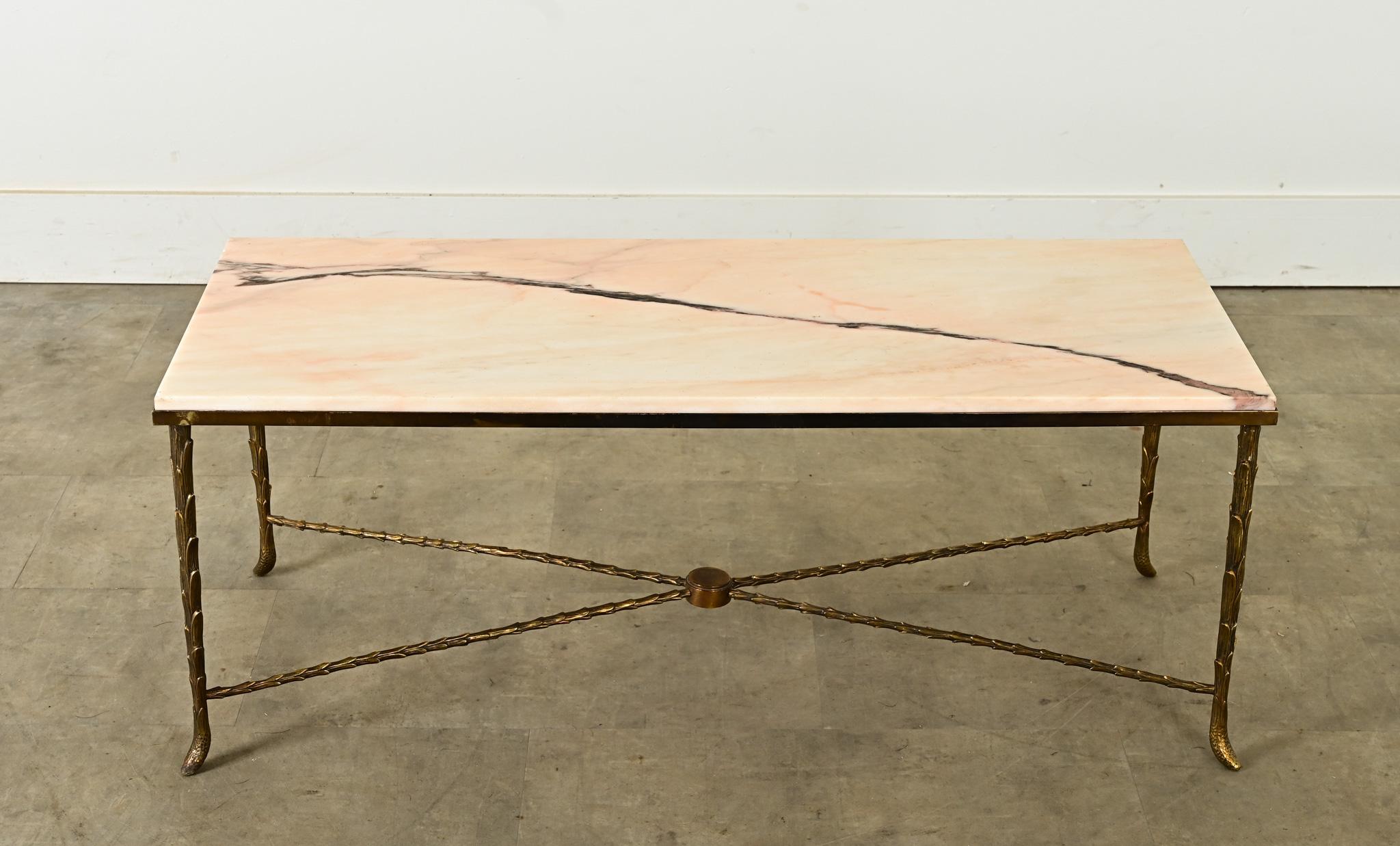 An enchanting cocktail table made in France, mid-20th century. Referencing the style and expertise of Maison Baguès, this creation has a pastel pink marble top, streaked with a gray vein, inset and secured by a low frame along the edges. The elegant
