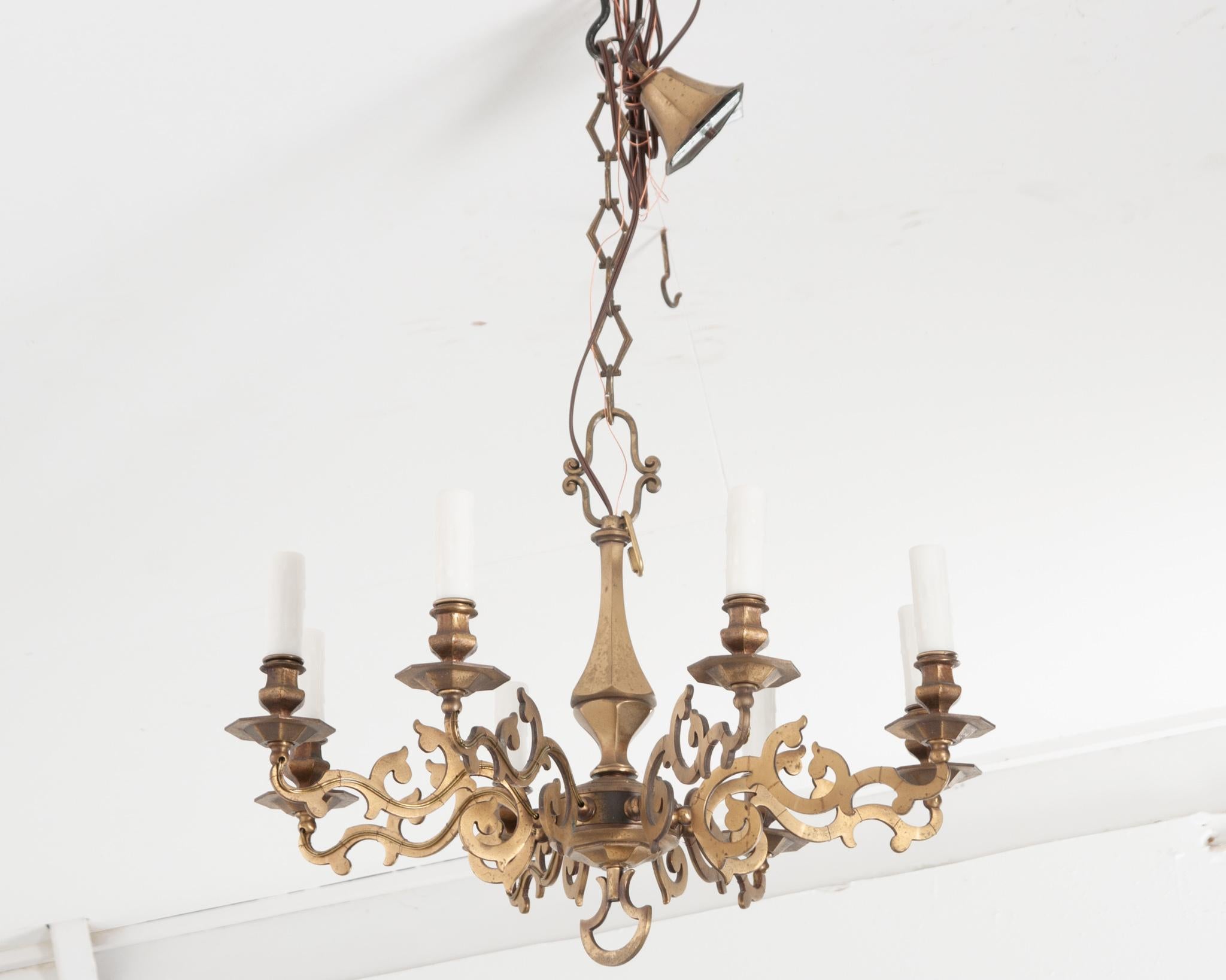 An elegant brass chandelier from 19th century France to elevate any space. Eight scrolling arms and unique shaped chain links emphasize the artful craftsmanship of this fixture. Canopy measures 4”x4”. Chain is 13-½” in length. Cleaned and rewired
