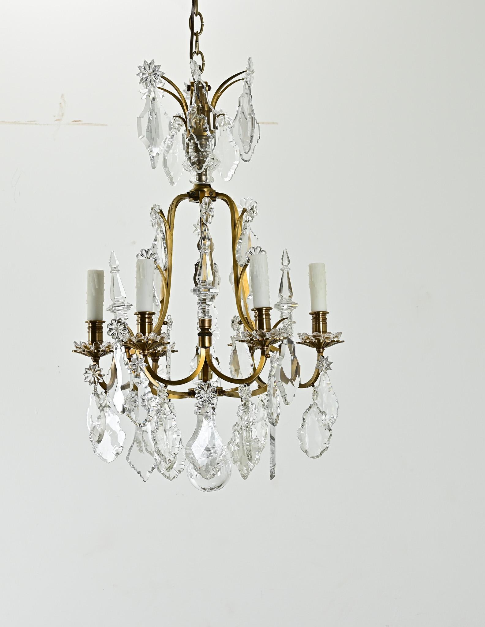 Un piccolo lampadario francese a 6 luci in ottone e cristallo del 1800. Gocce di cristallo tagliato e disegni floreali di cristallo pendono da sei bracci smerlati del lampadario con coperture di candele di cera finta. Pulita e cablata per l'impianto