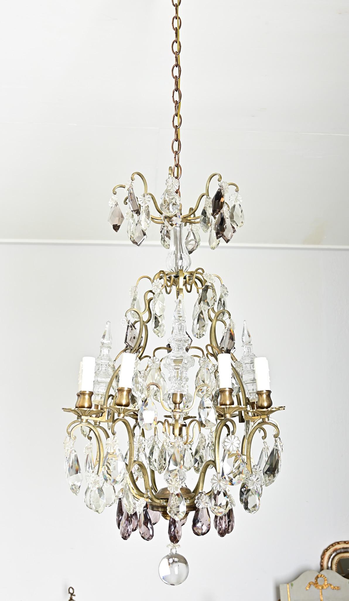 A dazzling 19th century French nine-light brass and crystal chandelier to illuminate your dining room, foyer, or other space in need of Belle Époque glamor. This statement chandelier has a multi-tiered frame that is dripping with teardrops, prisms