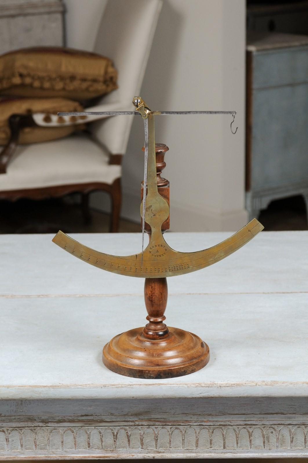 A French brass fabric scale from the 19th century with wooden base, signed Robert A Vienne. Created in France during the 19th century, this fabric scale, made of brass, is mounted on a turned wooden base with circular plinth. Signed Robert A Vienne,