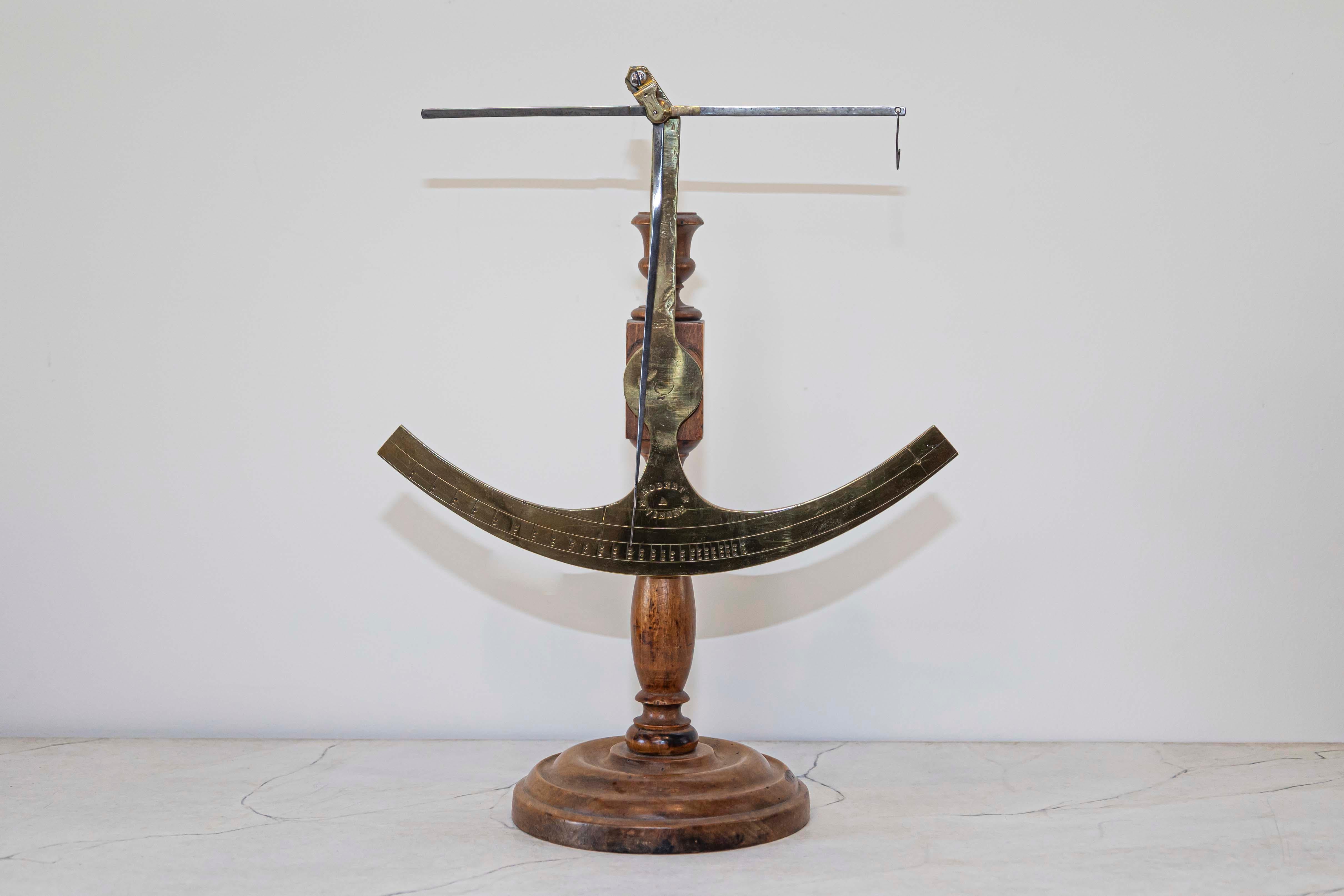 Une balance à tissu française en laiton du 19ème siècle avec une base en bois, signée Robert A Vienne. Créée en France au XIXe siècle, cette balance à tissu, en laiton, est montée sur un socle circulaire en bois tourné. Signée Robert A Vienne, la