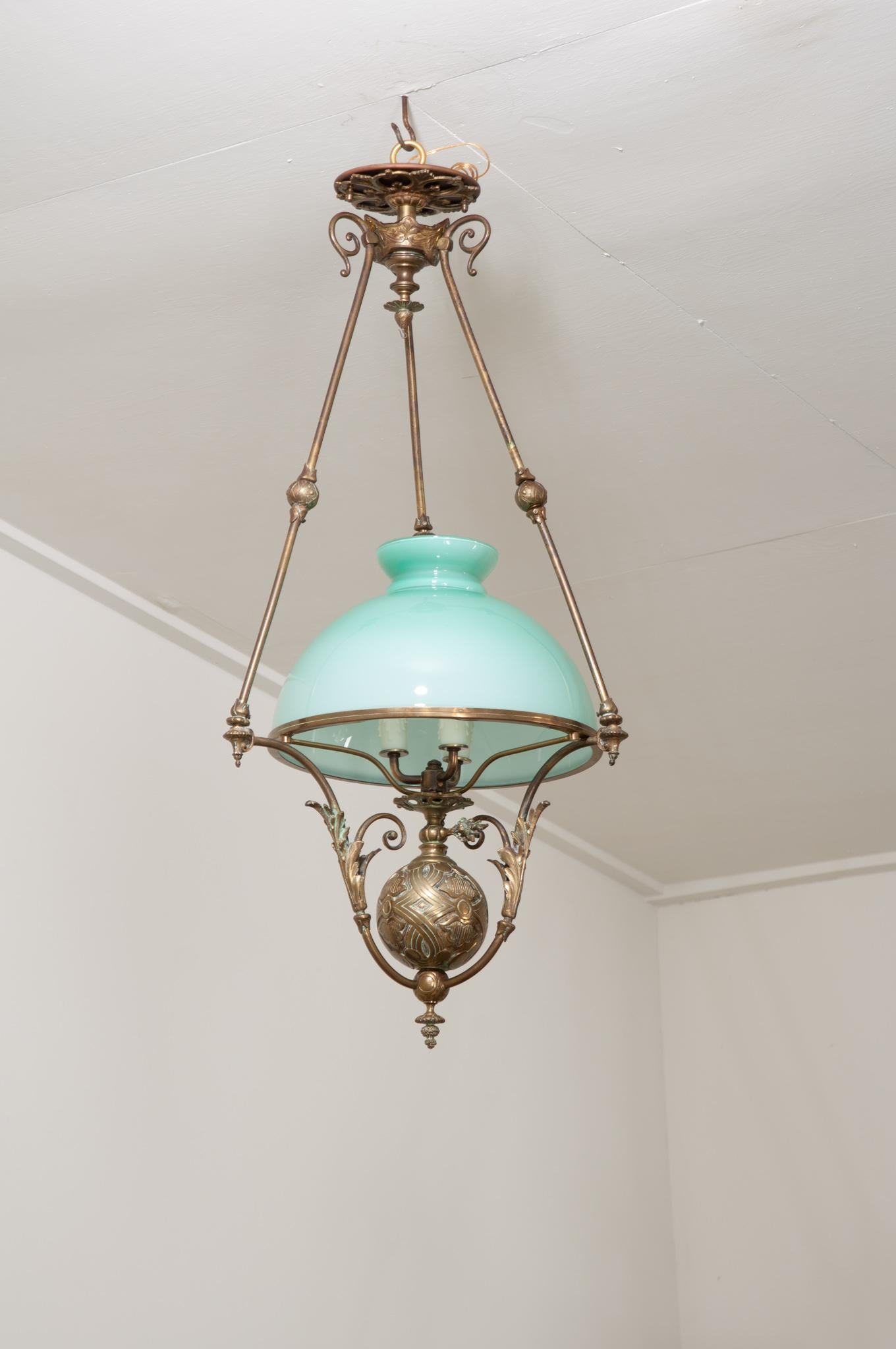 A 19th century French Beaux-Arts style brass and glass oil lamp chandelier with large aquamarine blue glass dome shade. Three scrolling cast brass arms with decorative finial centers descend from an ornate cast brass rosette and detailed cast brass