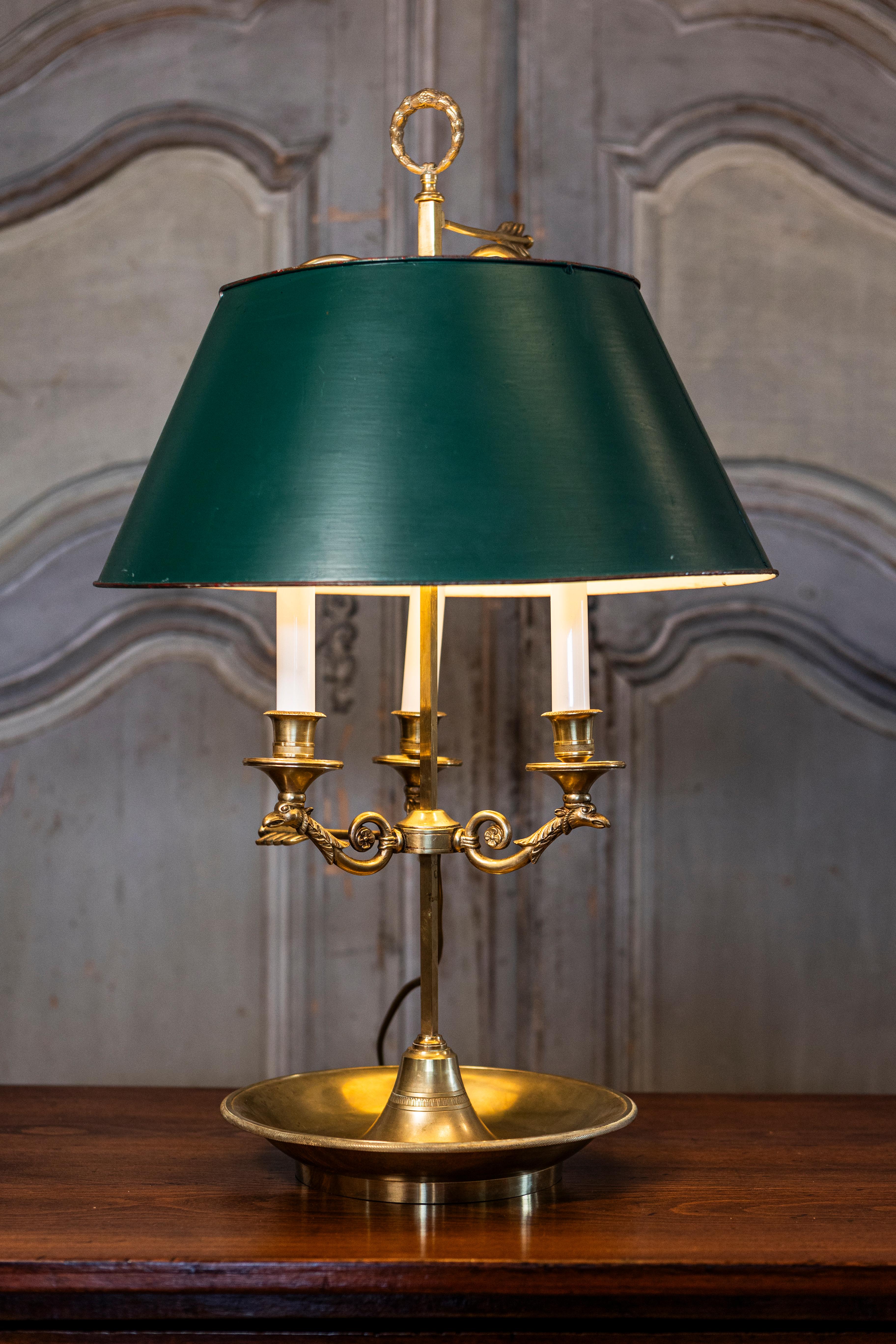 A French brass three-light bouillotte table lamp from the 19th century with green painted tôle shade, bird motifs and scrolling arms. This exquisite French bouillotte table lamp from the 19th century radiates timeless elegance, making it a