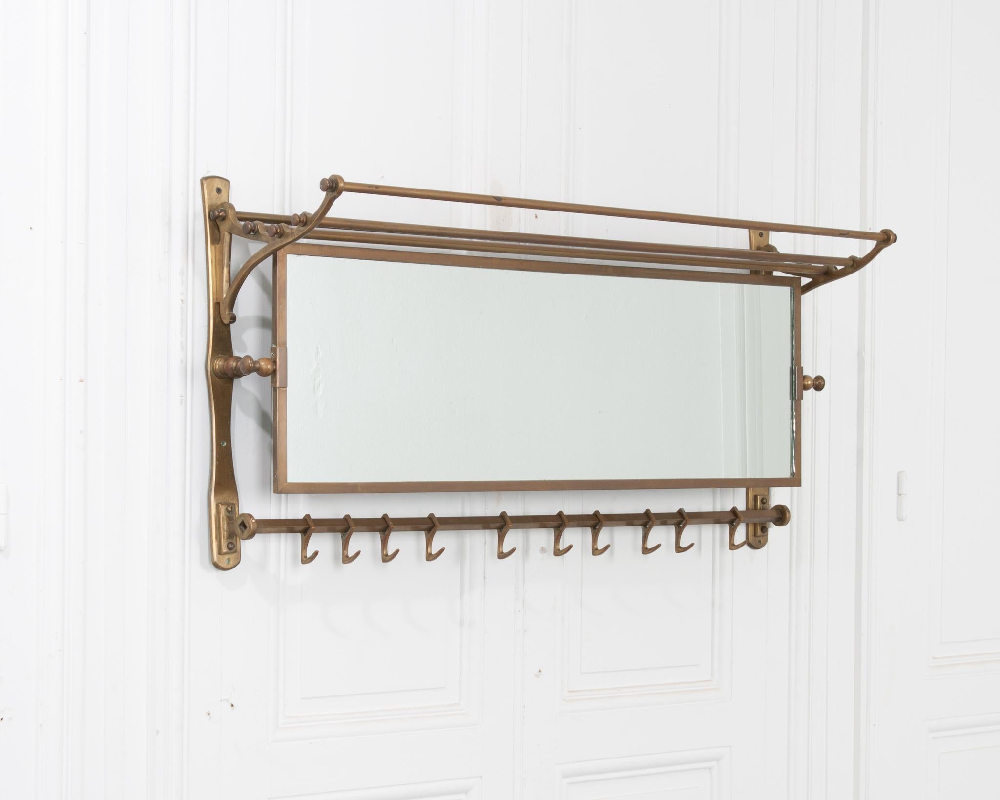 This French 19th century brass train rack is in great condition! The original swivel mirror adjusts to the proper angle for viewing. Nine sliding hooks and an upper shelf make this piece ideal in a bathroom for towels and robes or in an entryway